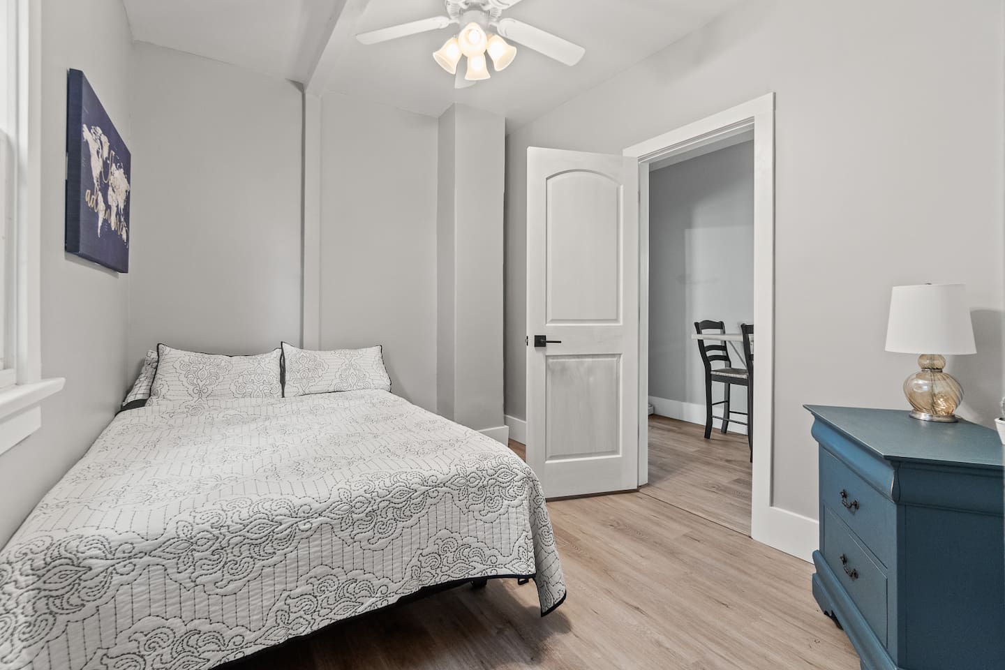 Double bed with ceiling fan, hardwood floors, and natural light.