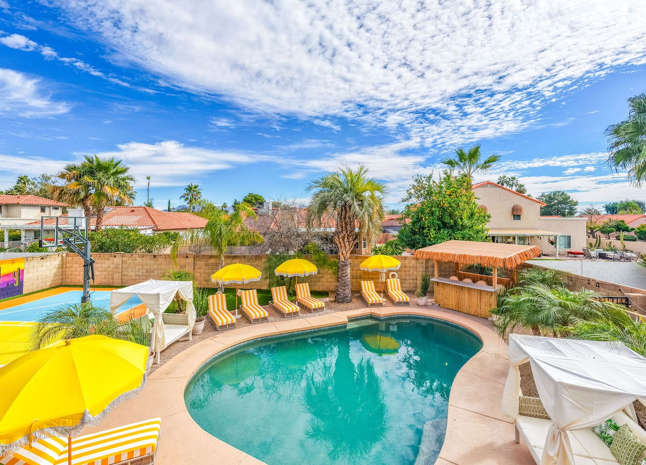 Resort-style pool area with loungers, yellow umbrellas, and desert views—a vacation oasis steps from the home.