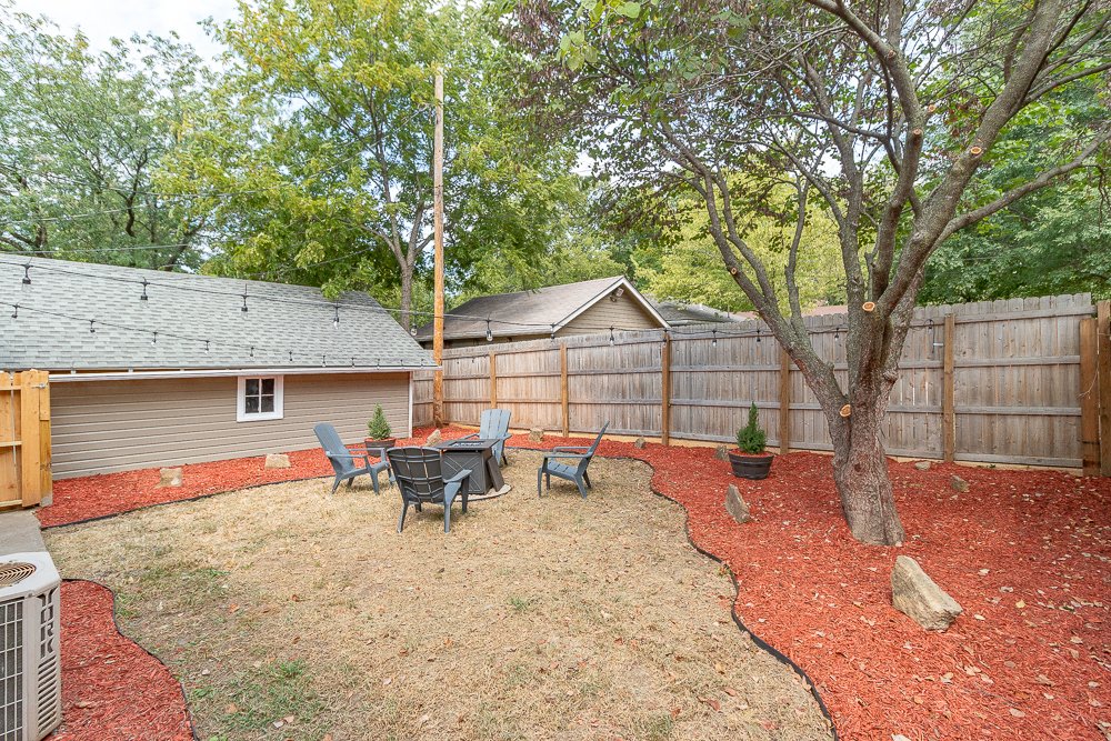Enjoy quiet evenings in this inviting backyard featuring a fire pit and comfortable Adirondack chairs.