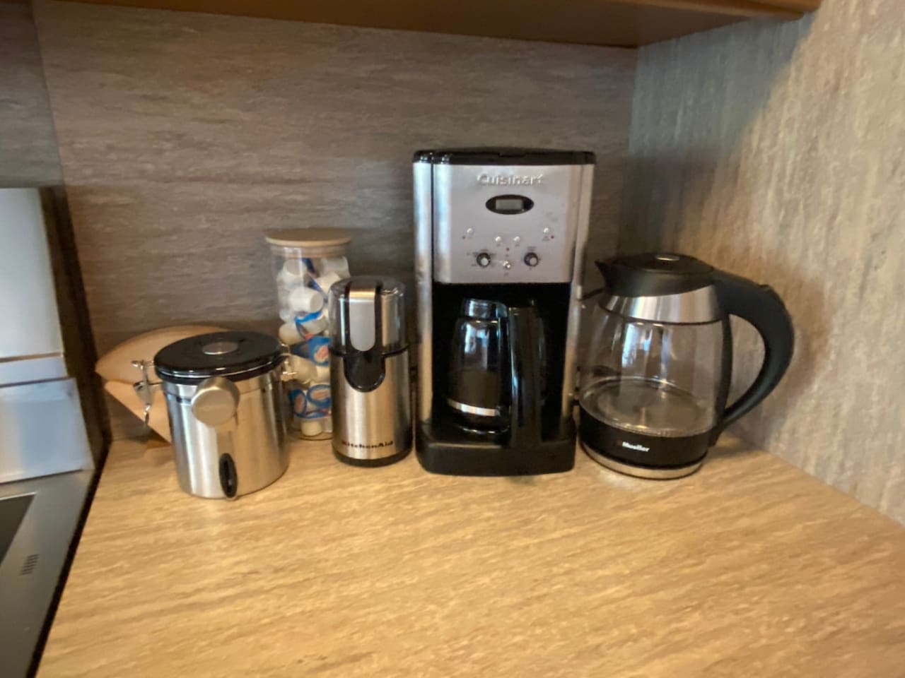 Coffee maker, coffee beans, coffee grinder, filters, sweetened creamer, and a hot water kettle are provided.