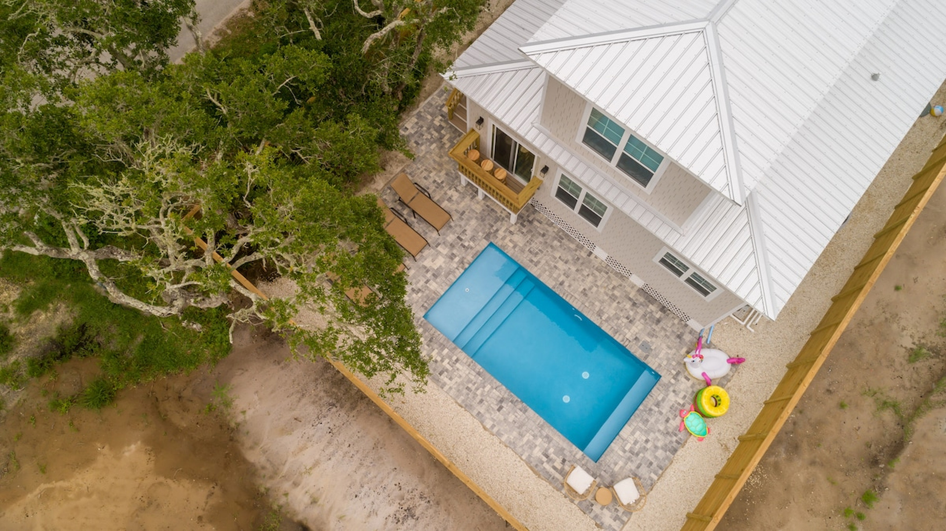 From above you can see how the whole back of the property is given over to the pool - pavers, loungers, and a fence around all of it. The rear steps come down from the living room, so the water is never far.