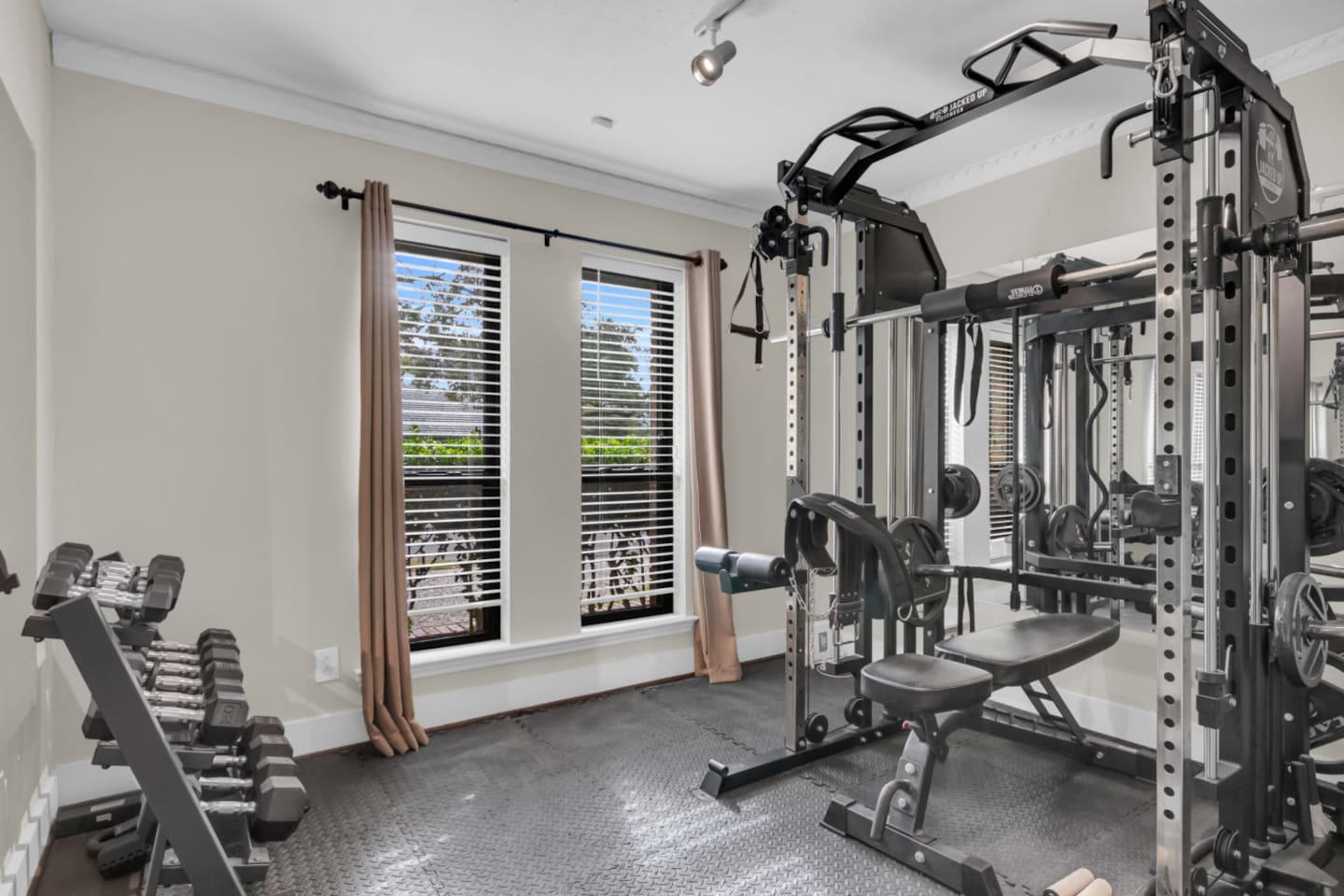 Private home gym equipped with a full weight rack, dumbbells, and strength-training equipment, offering a convenient space for workouts without leaving the house.