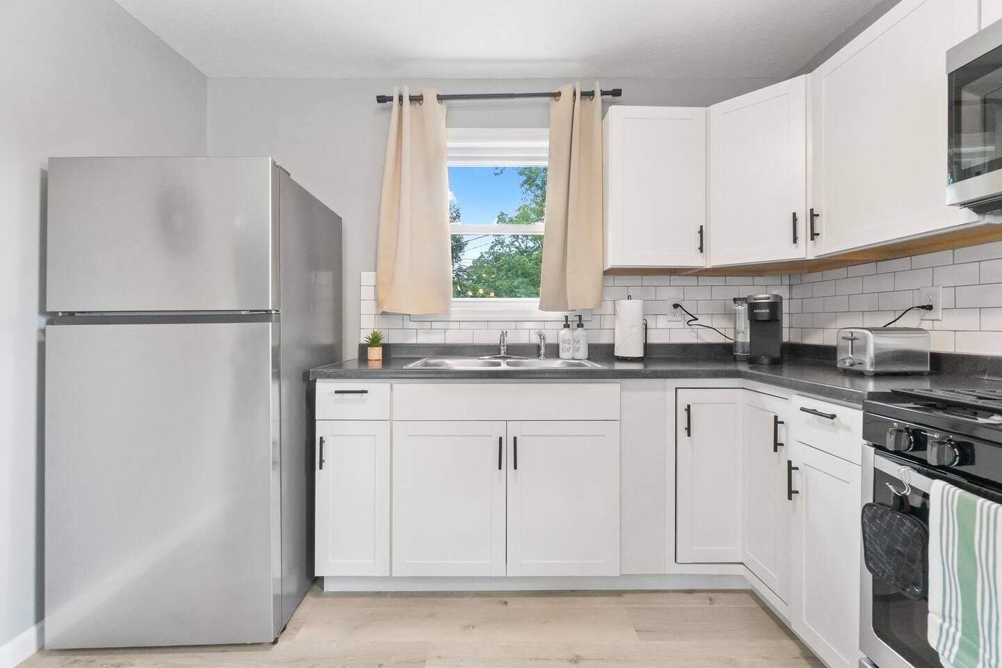 Well-equipped kitchen featuring a fridge, Keurig, toaster, stove with oven, and a variety of kitchenware for all your cooking needs.