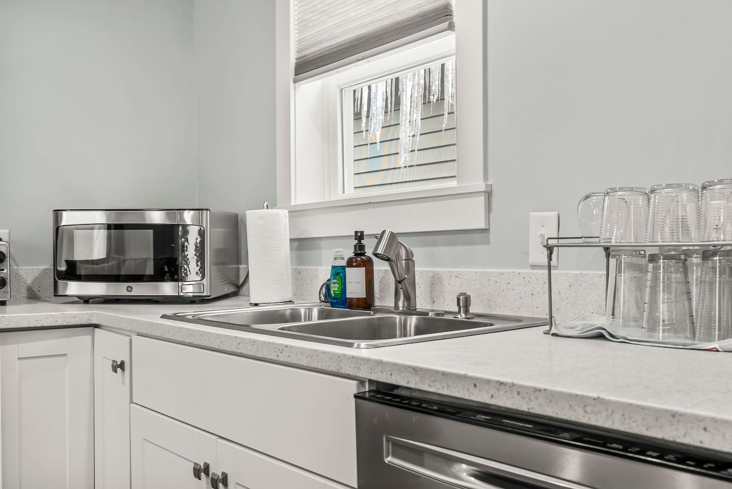 Modern kitchen sink area with stainless steel double basin, pull-down faucet, and natural light from the window.