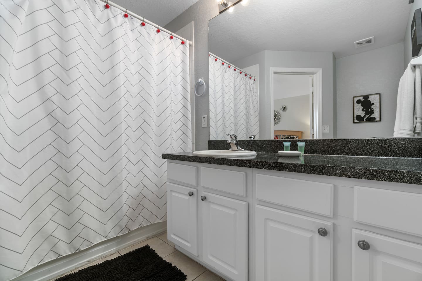 - Sleek bathroom with white cabinetry, granite countertop, and large mirror  
- Chevron pattern shower curtain adds a modern touch to the clean design  
- Functional layout ideal for refreshing after a day of adventures  