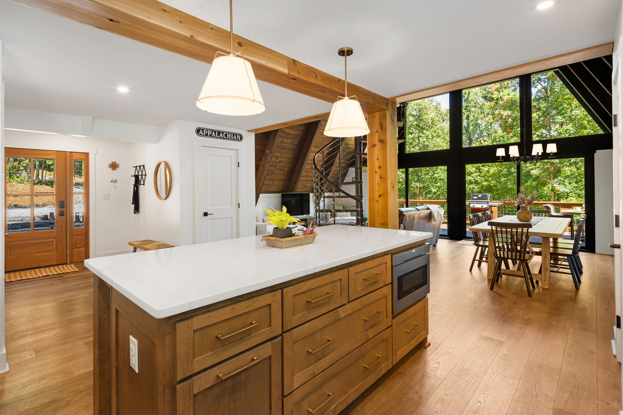 A view of the living area and dining room from the kitchen and the wall of windows overlooking the main deck. 