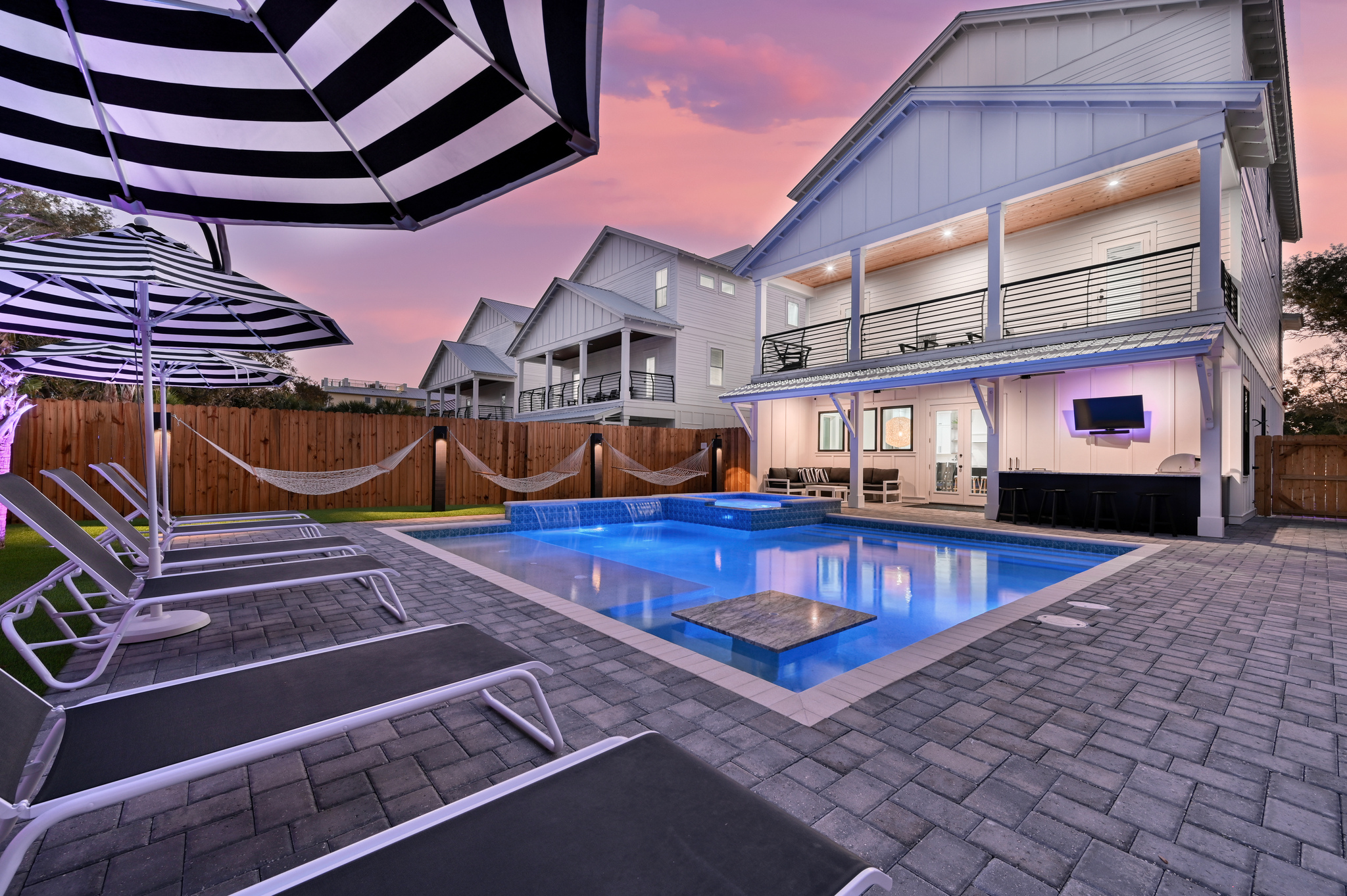 Astroturf yard with Luxury lounges, matching umbrellas, poolside hammocks, putting green, and backyard lighting