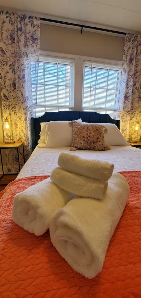 Peaceful bedroom featuring a plush bed with crisp white linens, a velvet headboard, and warm lighting—perfect for a restful night’s sleep.