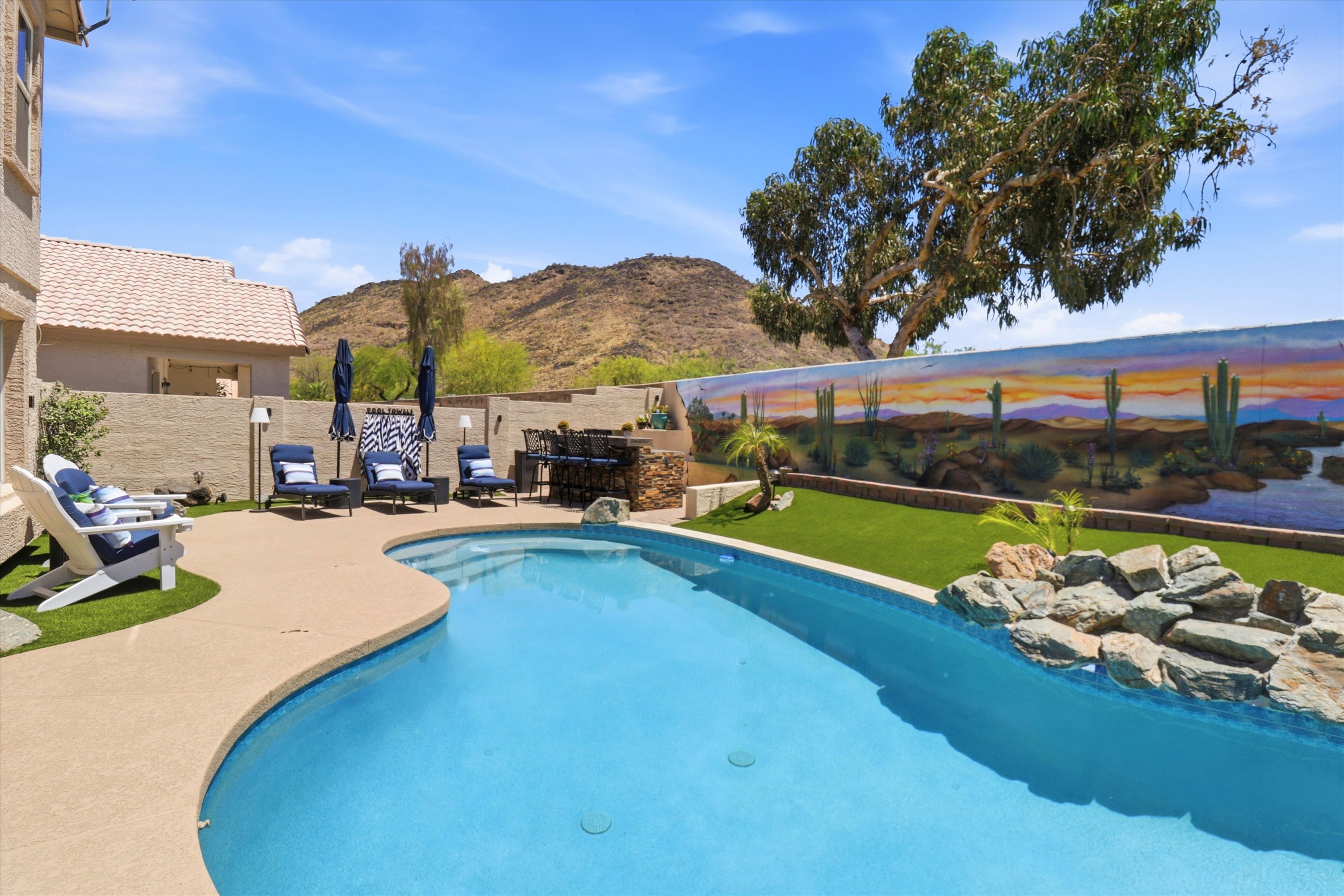 Private backyard unheated pool with lounge seating, mountain views, and a colorful desert mural for a standout outdoor retreat.