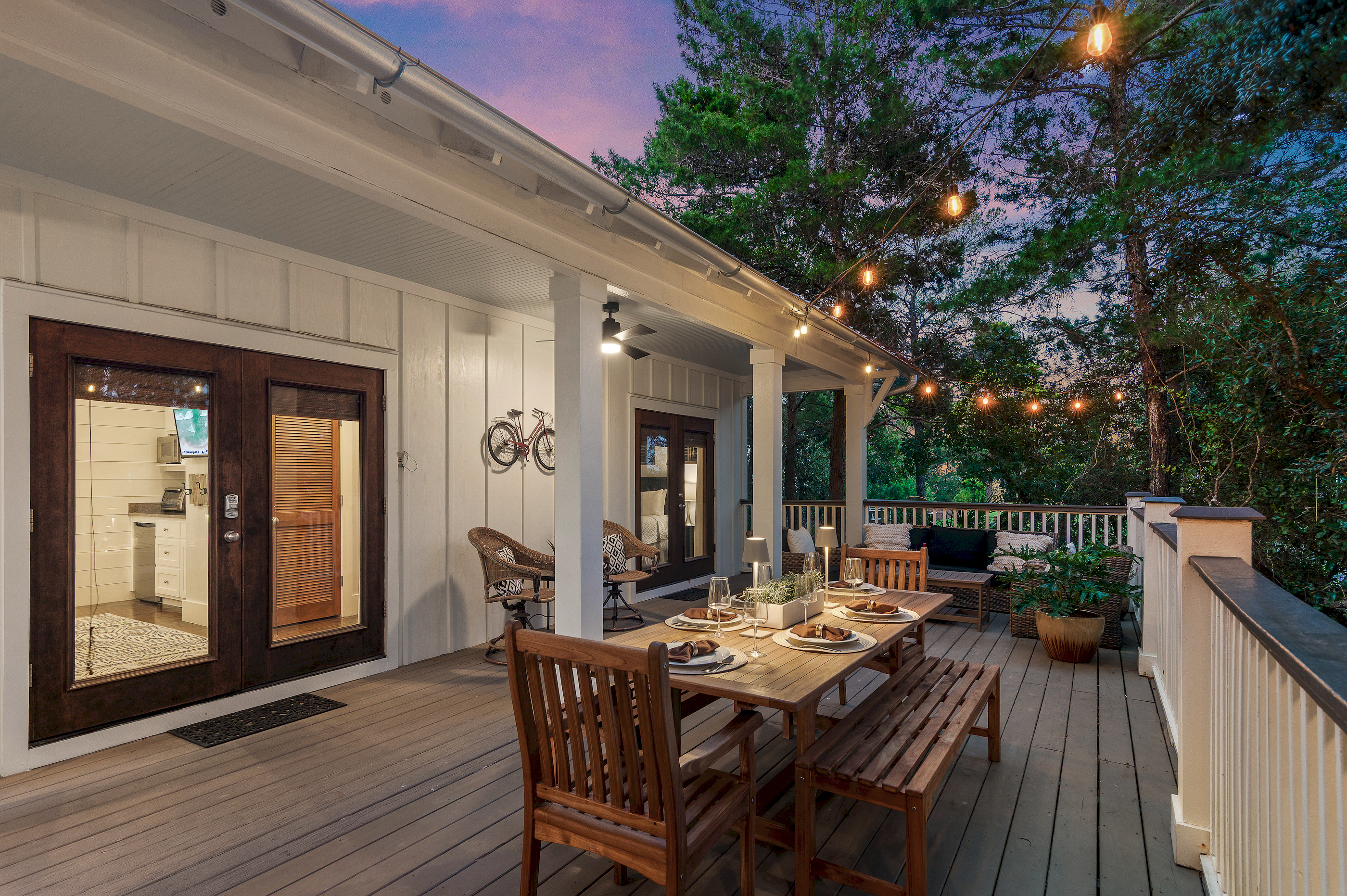 The spacious porch is softly lit by glowing string lights, creating the perfect setting for evening dinner and conversations.