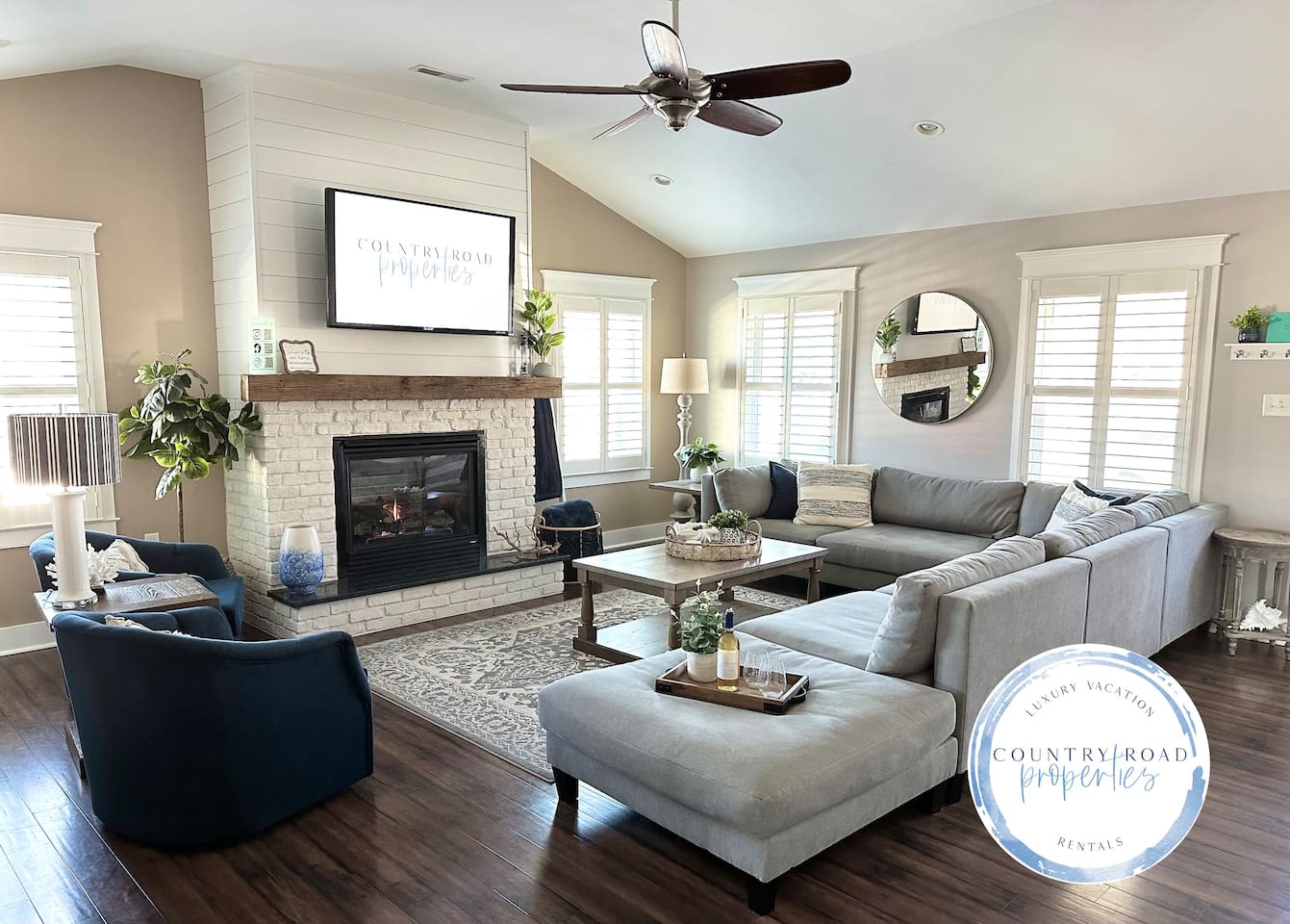 Relax in the bright, airy living room featuring a cozy white brick fireplace, a massive sectional, and stylish navy armchairs. It’s the ultimate space for family movie nights or wine by the fire during your dream getaway.