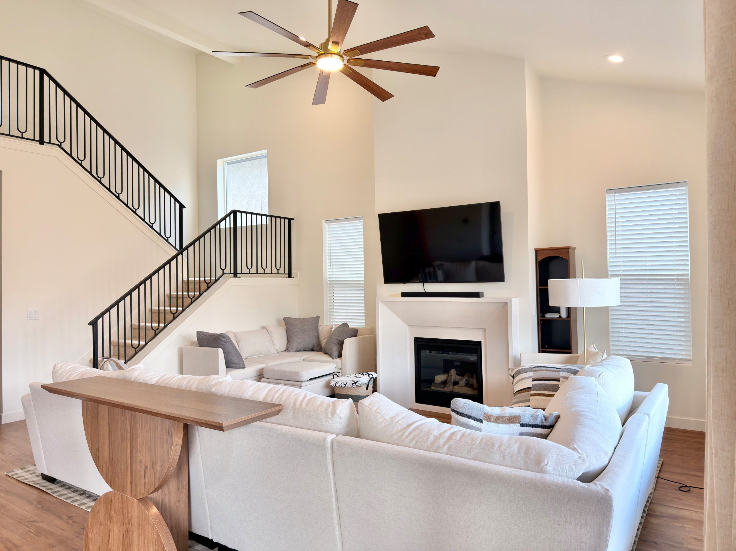 Stylish open-concept living room with elegant staircase, cozy seating, and abundant natural light.