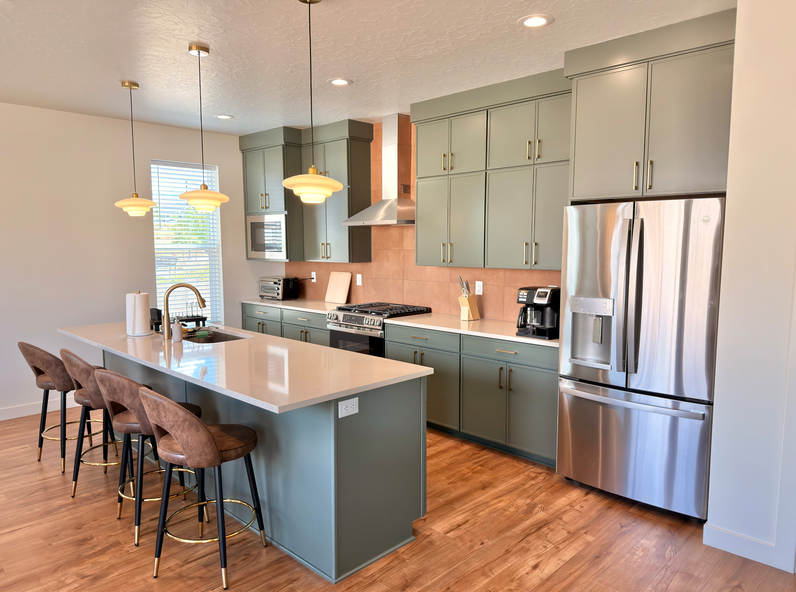 Chef’s dream kitchen with forest-green cabinetry, quartz counters, and a large island with seating.