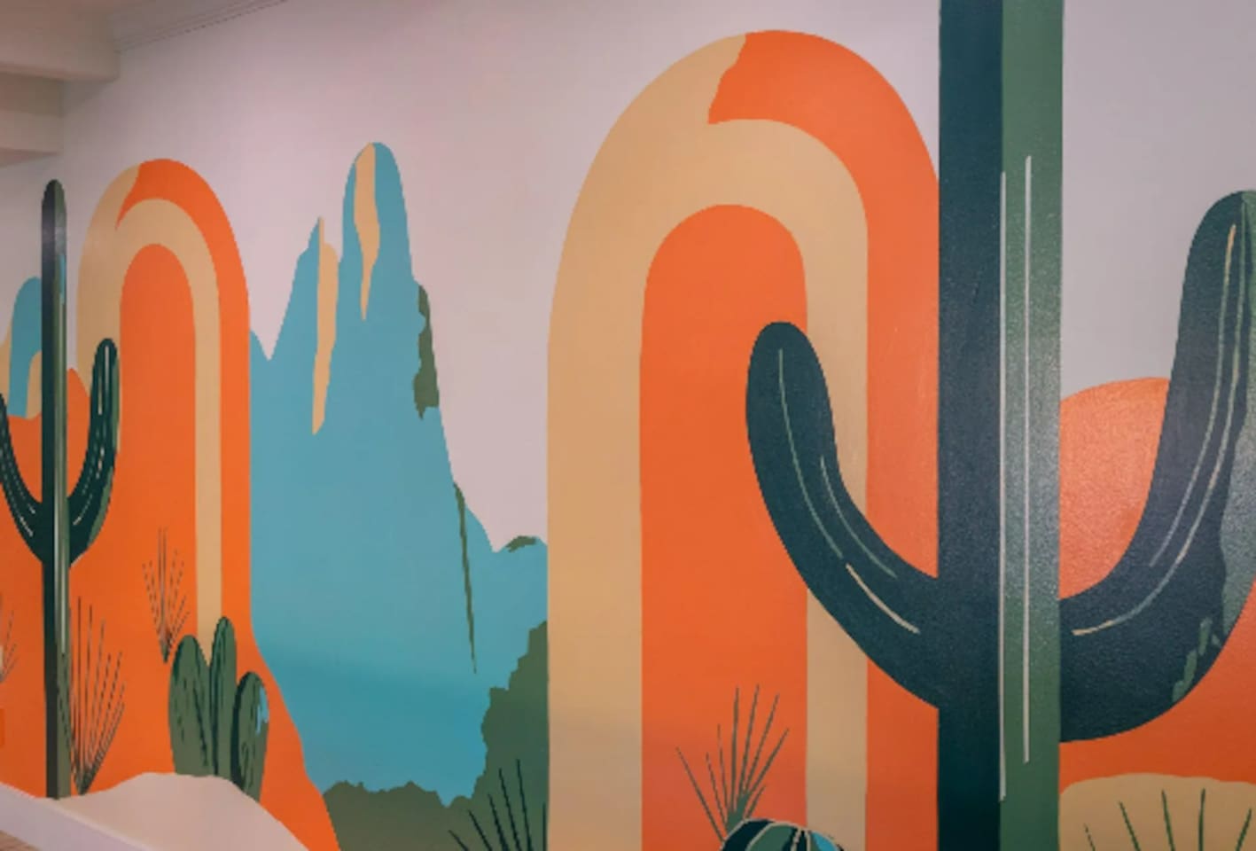 A bold, hand-painted desert mural adds color and personality to the space, a fun backdrop for photos.