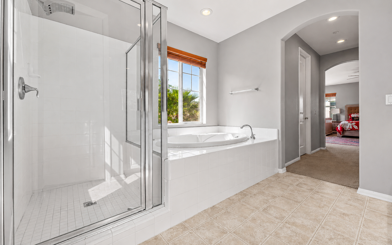 Bathroom with a glass shower, soaking tub, and easy access from the nearby bedroom.