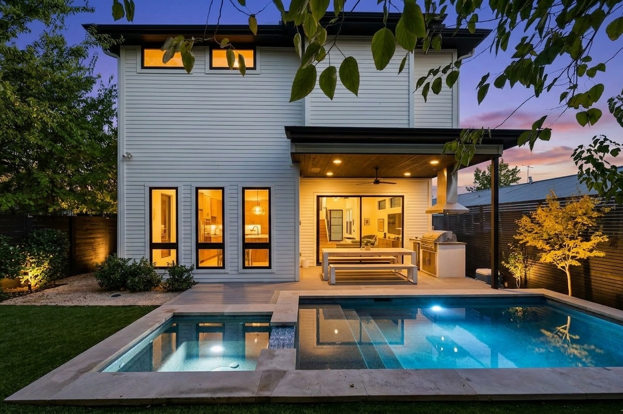 Twilight glow highlights the pool and warmly lit interior of this East Austin home.