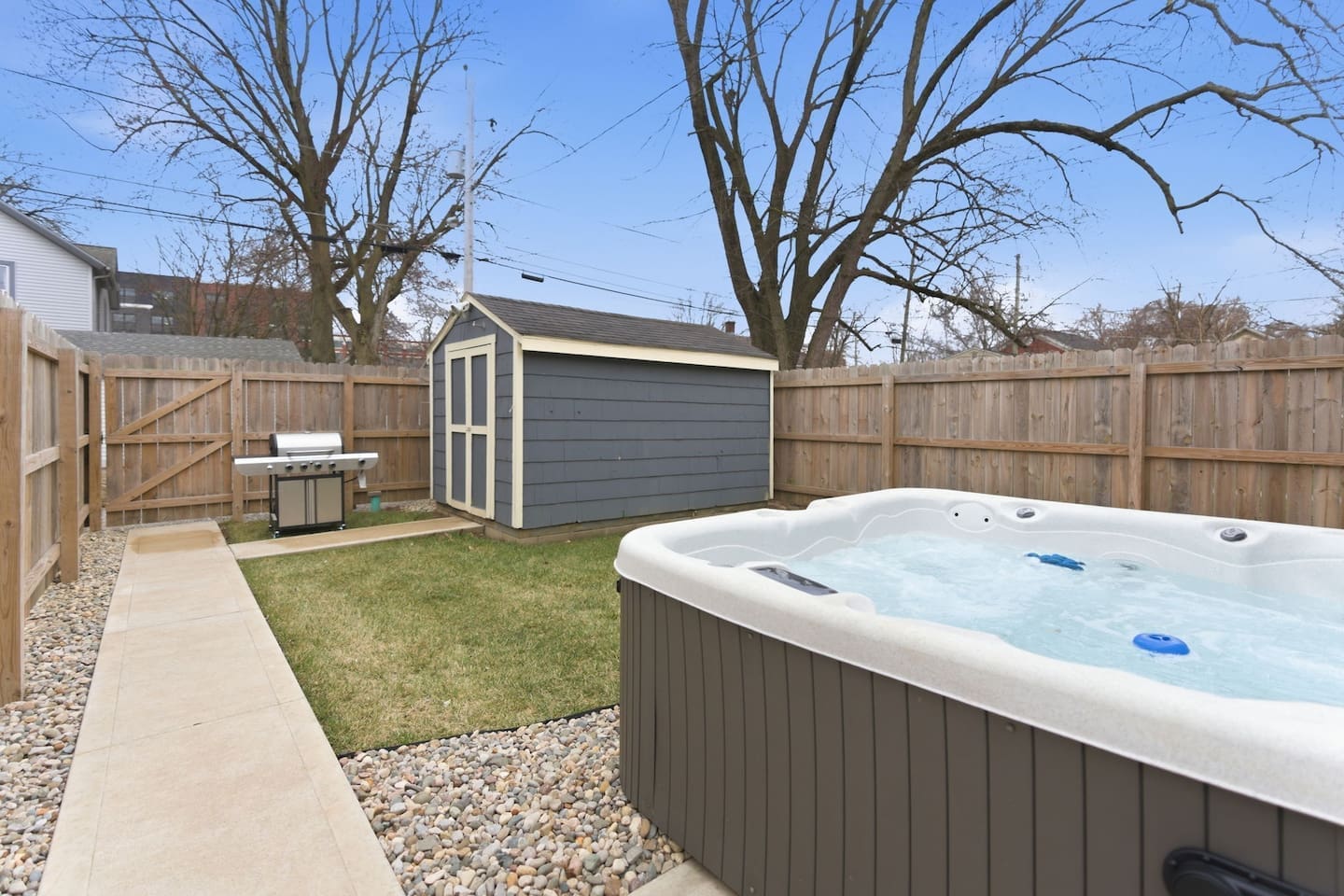 Private backyard with hot tub, grill, and storage shed for a complete outdoor experience