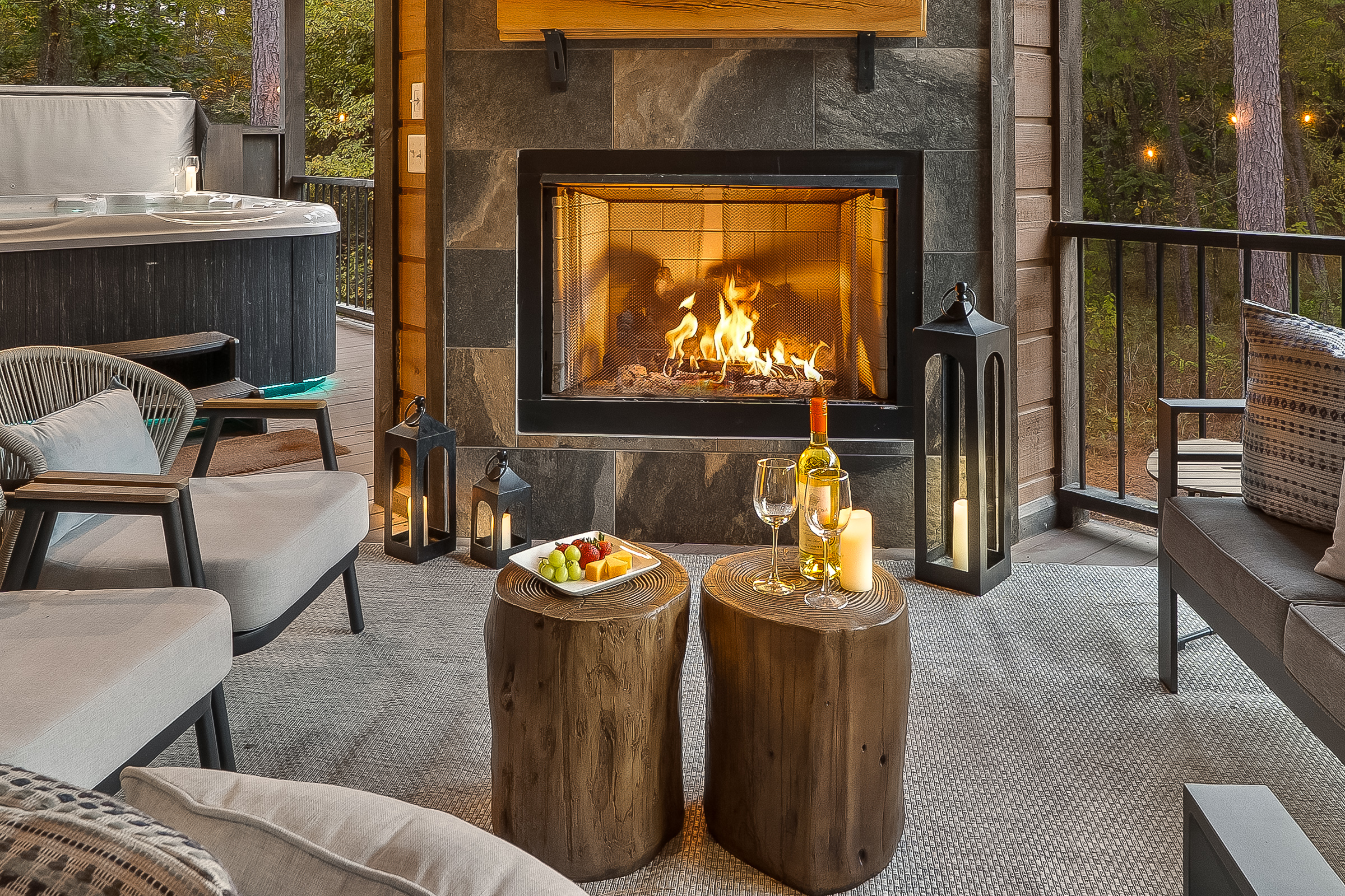 Resort inspired porch lounge with layered lanterns, cushioned seating, and a glowing fireplace as the focal point.