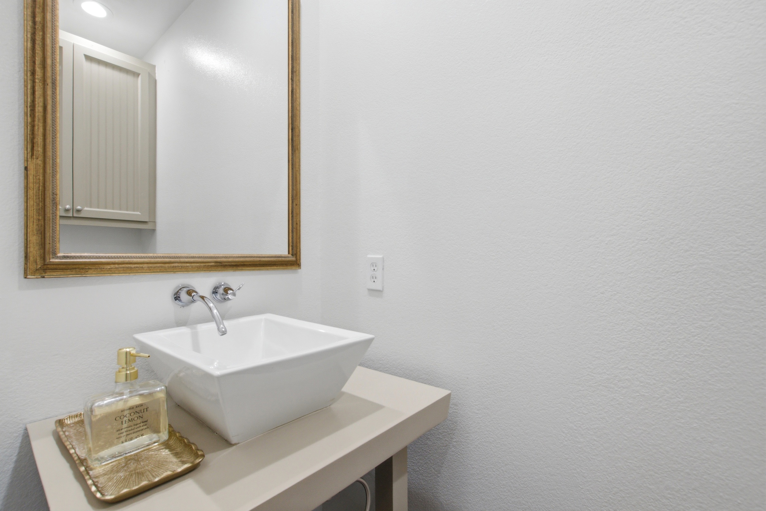 Half bath with vessel sink, modern gold fixtures, and a warm, minimal design. Conveniently located on the main living level for guests who need a quick stop between floors.