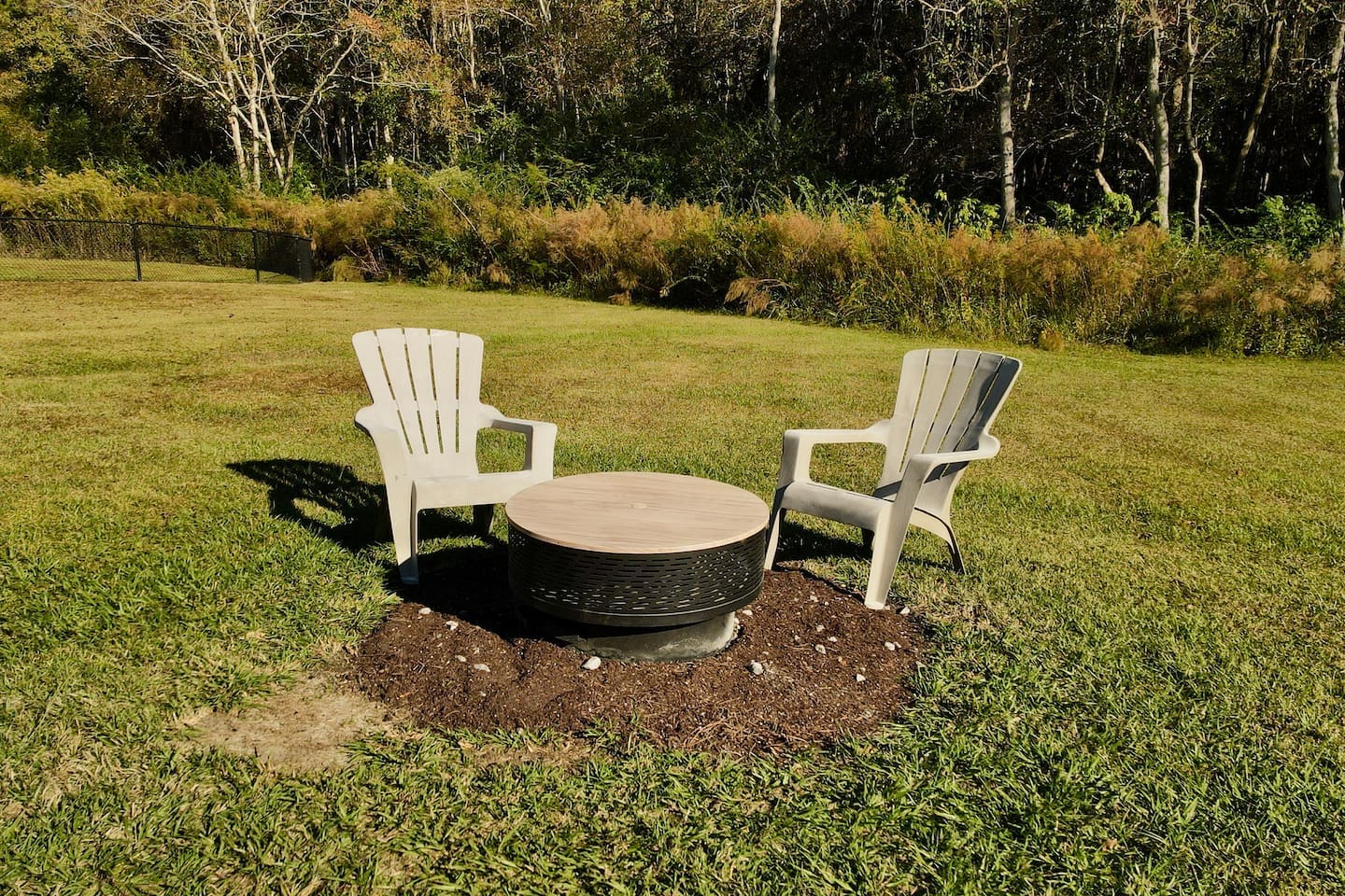 Two Adirondack-style chairs surround a circular fire pit, creating the perfect spot for evening relaxation.
