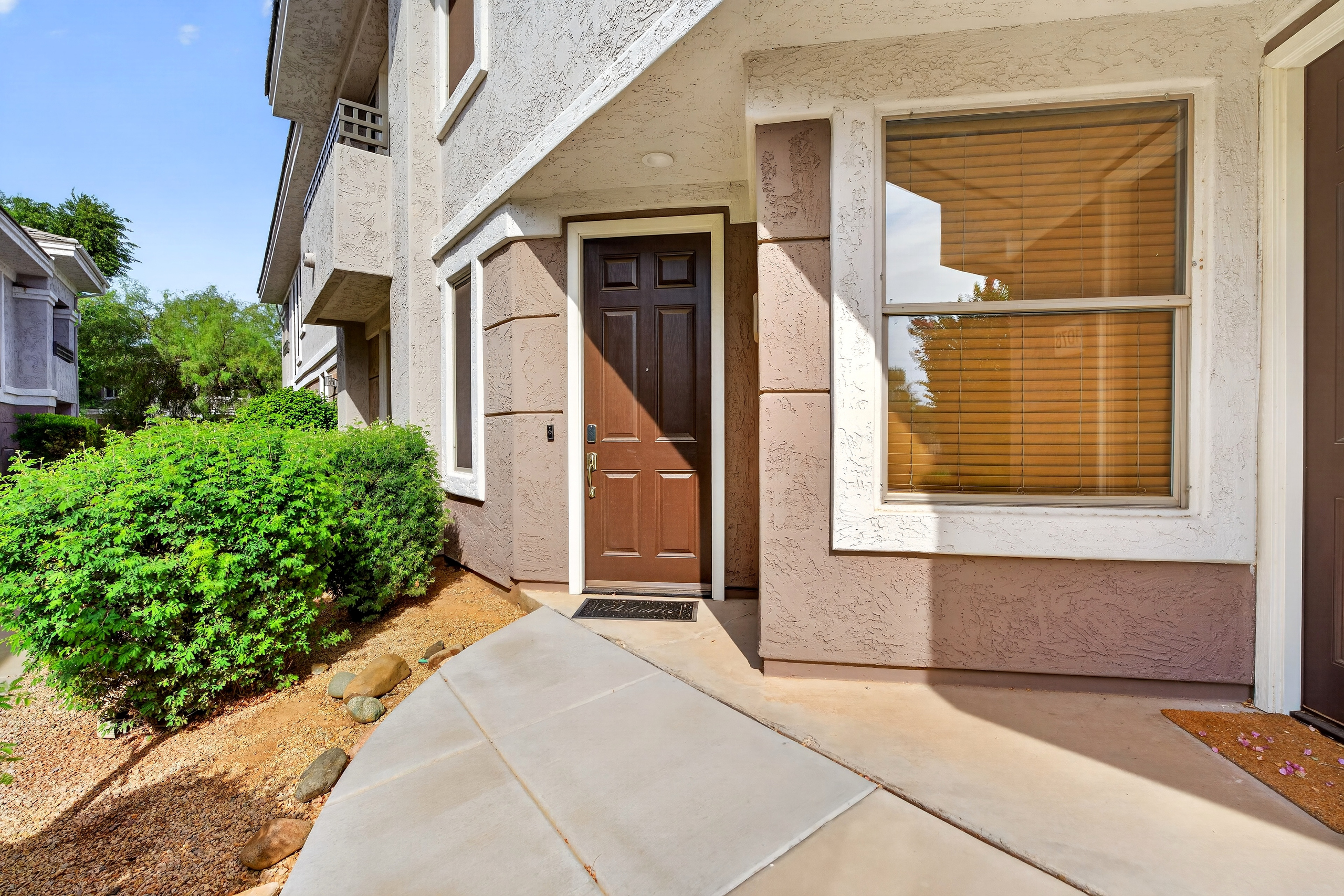 Covered front entry with sidewalk access, nearby landscaping, and a simple arrival path to the unit.