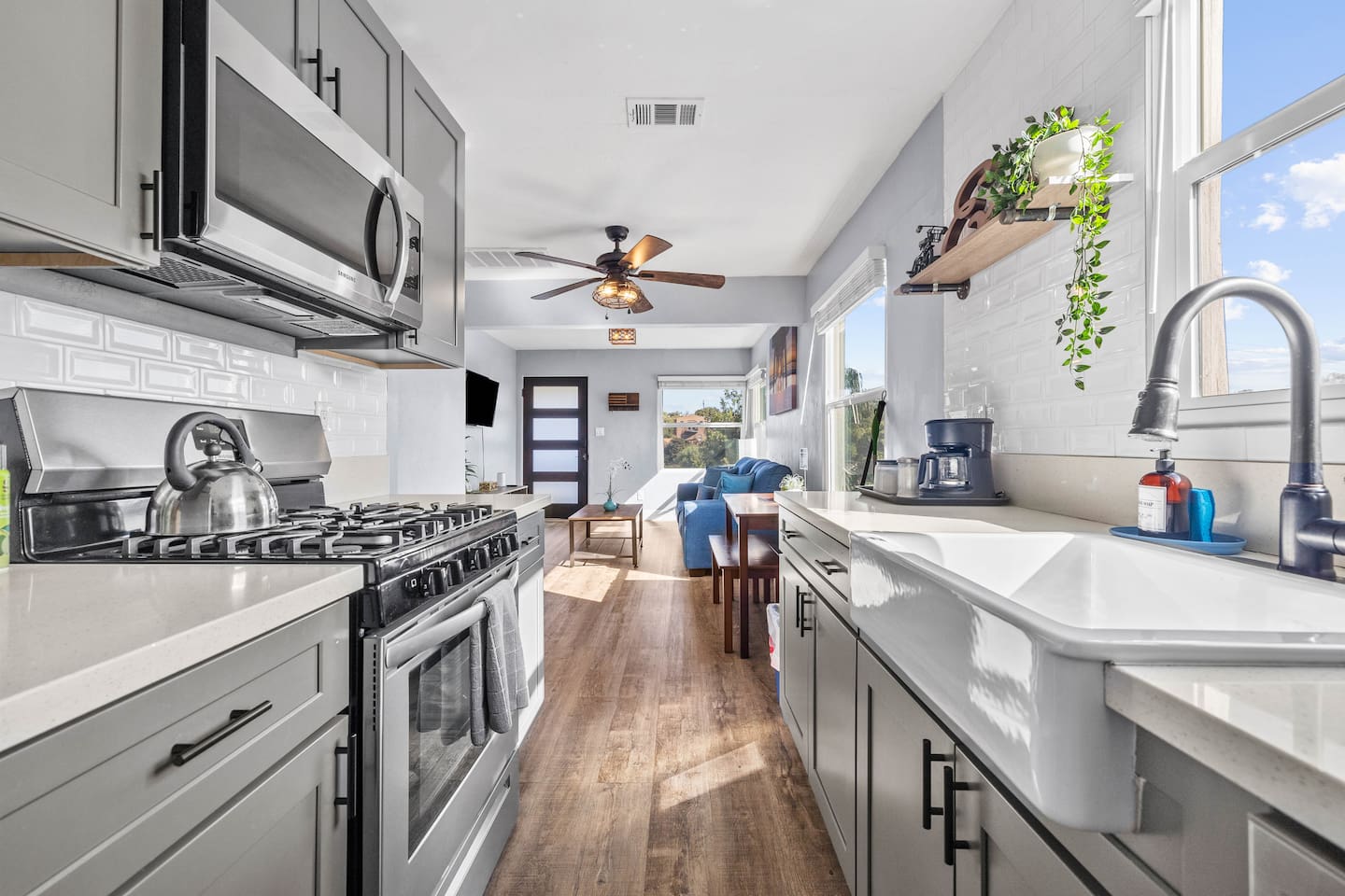 Spacious kitchen featuring a sleek sink with drawer storage, stove with microwave above and oven below, stylish refrigerator, and coffee maker. The open layout offers views of the cozy dining table and inviting living room, connected space.