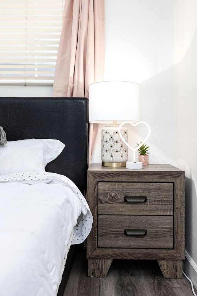 Thoughtfully styled with a cozy lamp, heart-shaped light, and decorative plant, your nightstand adds personality and warmth.

