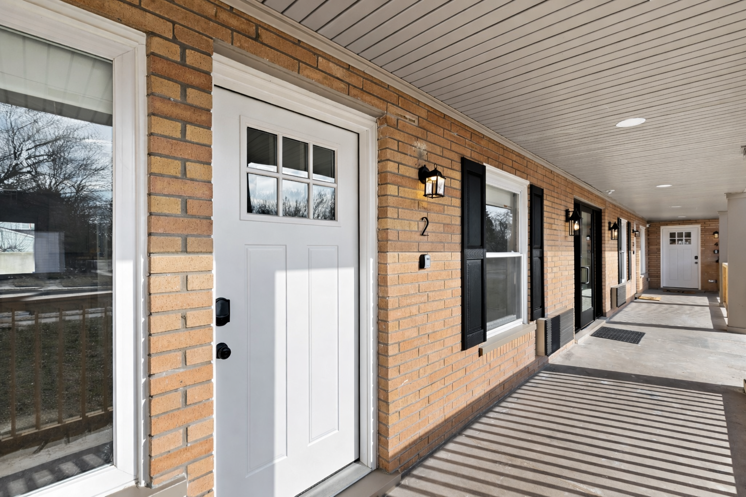 Inviting covered entry with a crisp white door, charming brick exterior, and soft lighting—offering a warm, private welcome from the moment you arrive.