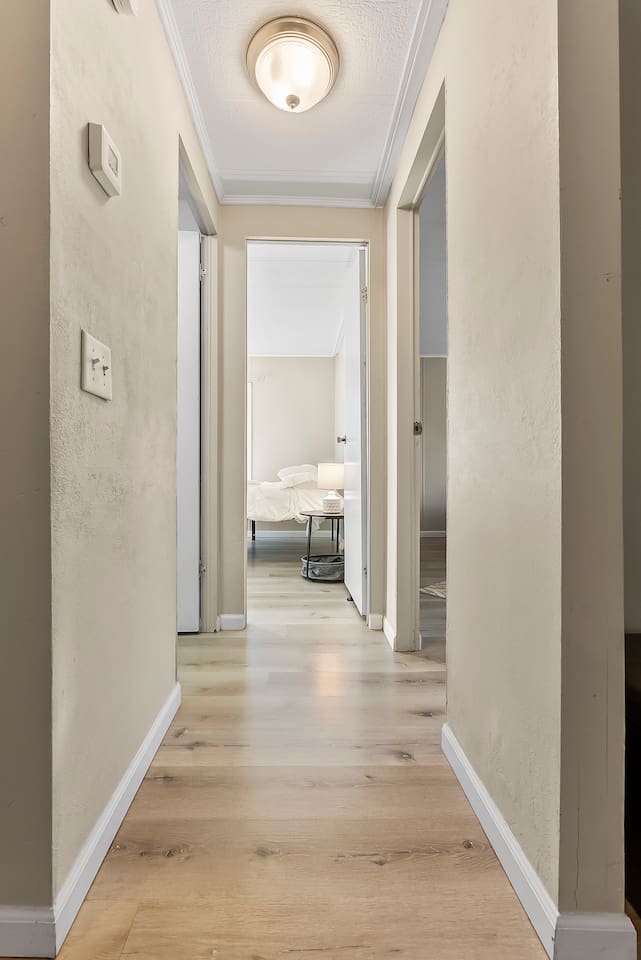Hallway view inside the home leading to bedrooms, showcasing updated flooring.