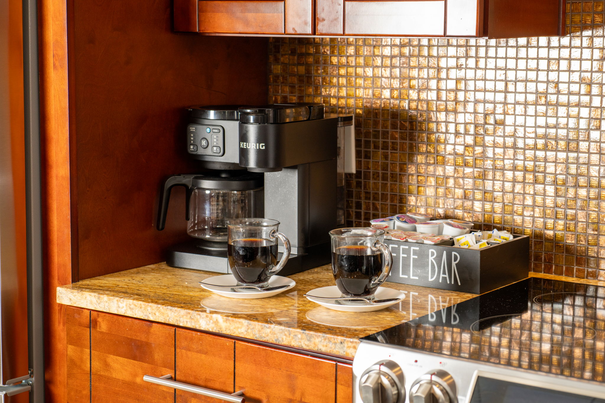 A dedicated coffee bar with a Keurig machine and mugs adds a cozy, personal touch to this polished kitchen.