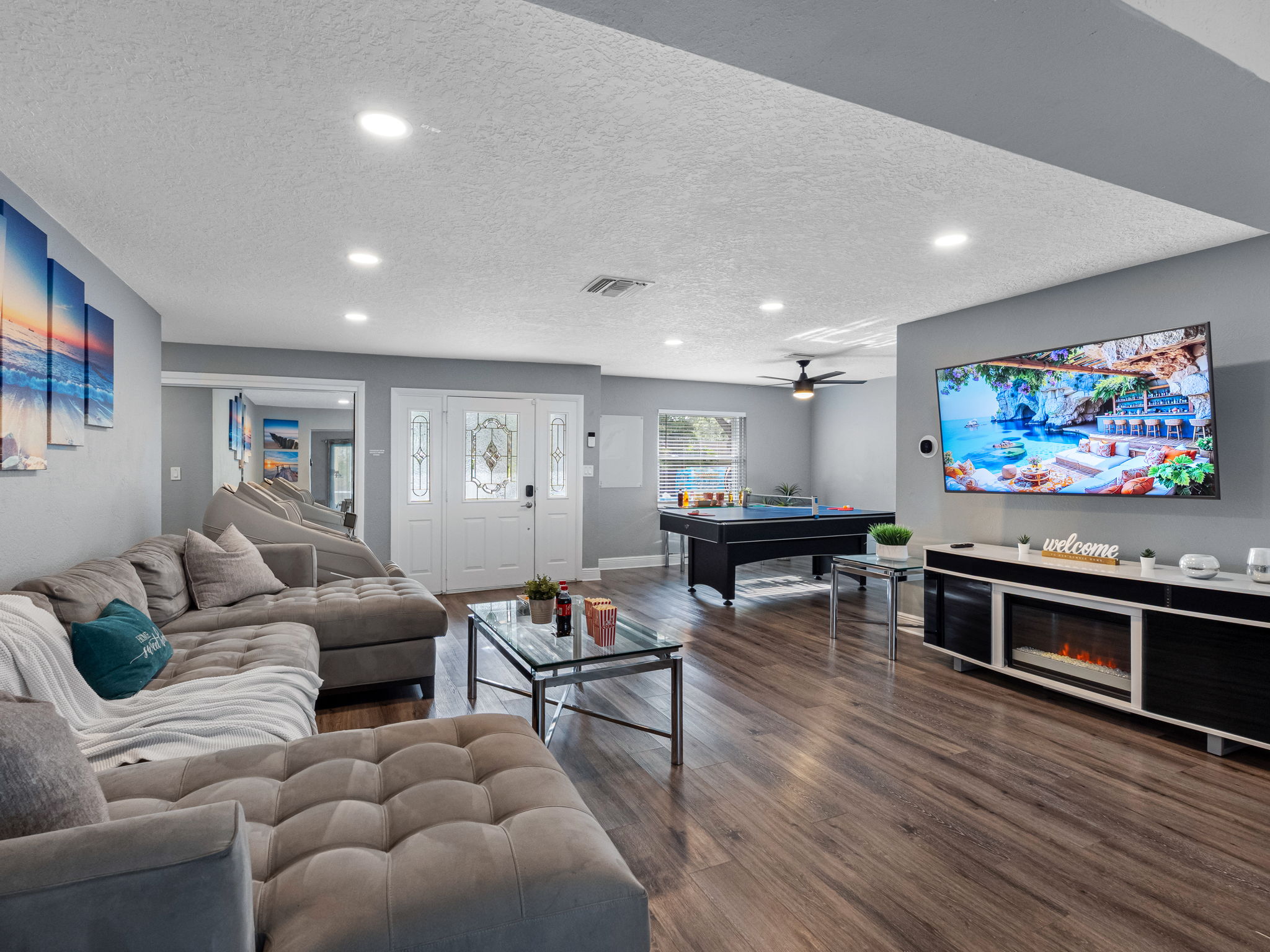 A large wall-mounted TV, cozy seating, and movie-time snacks on the coffee table make this space ideal for a home theater experience.