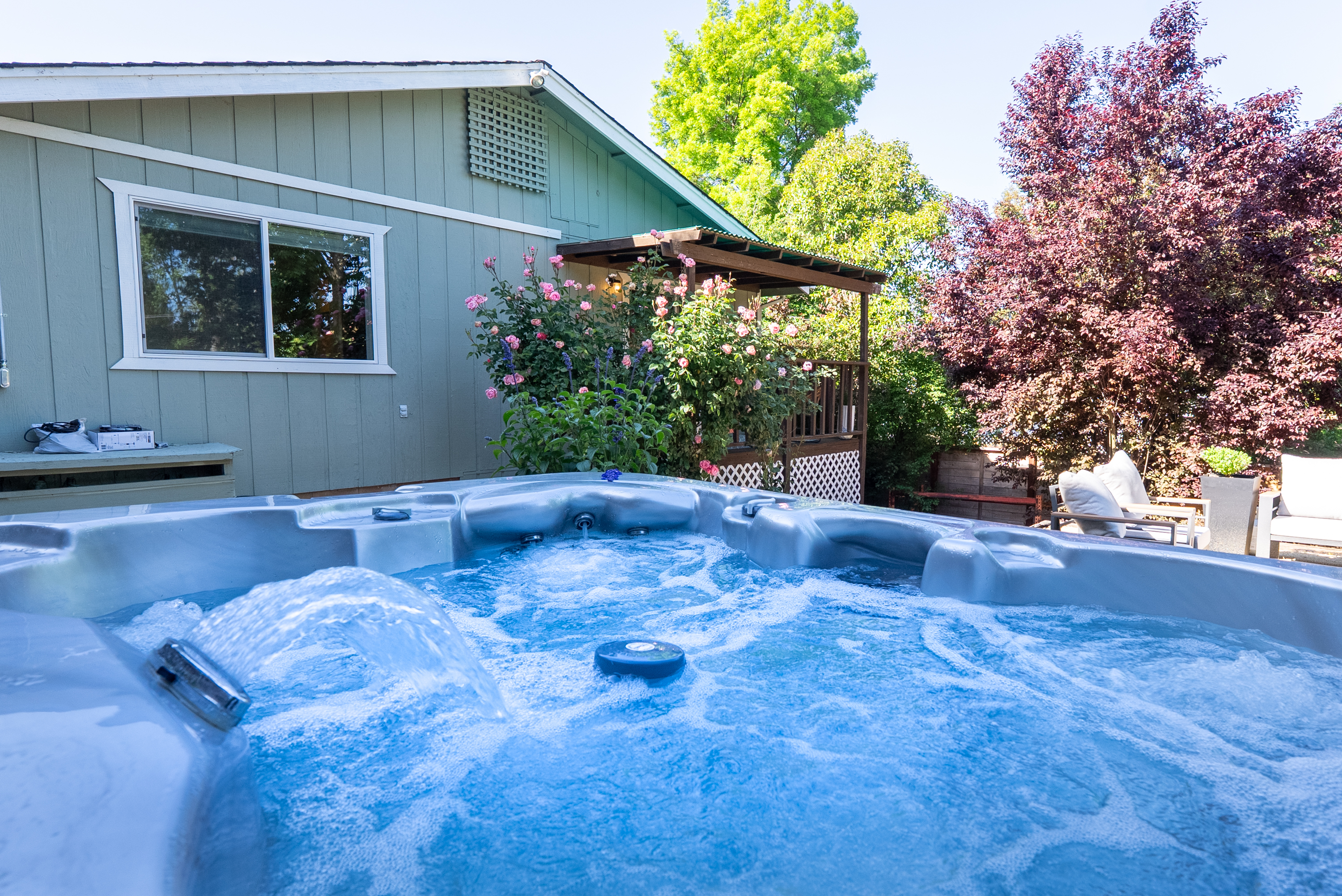 Unwind in the bubbling hot tub surrounded by lush garden views.