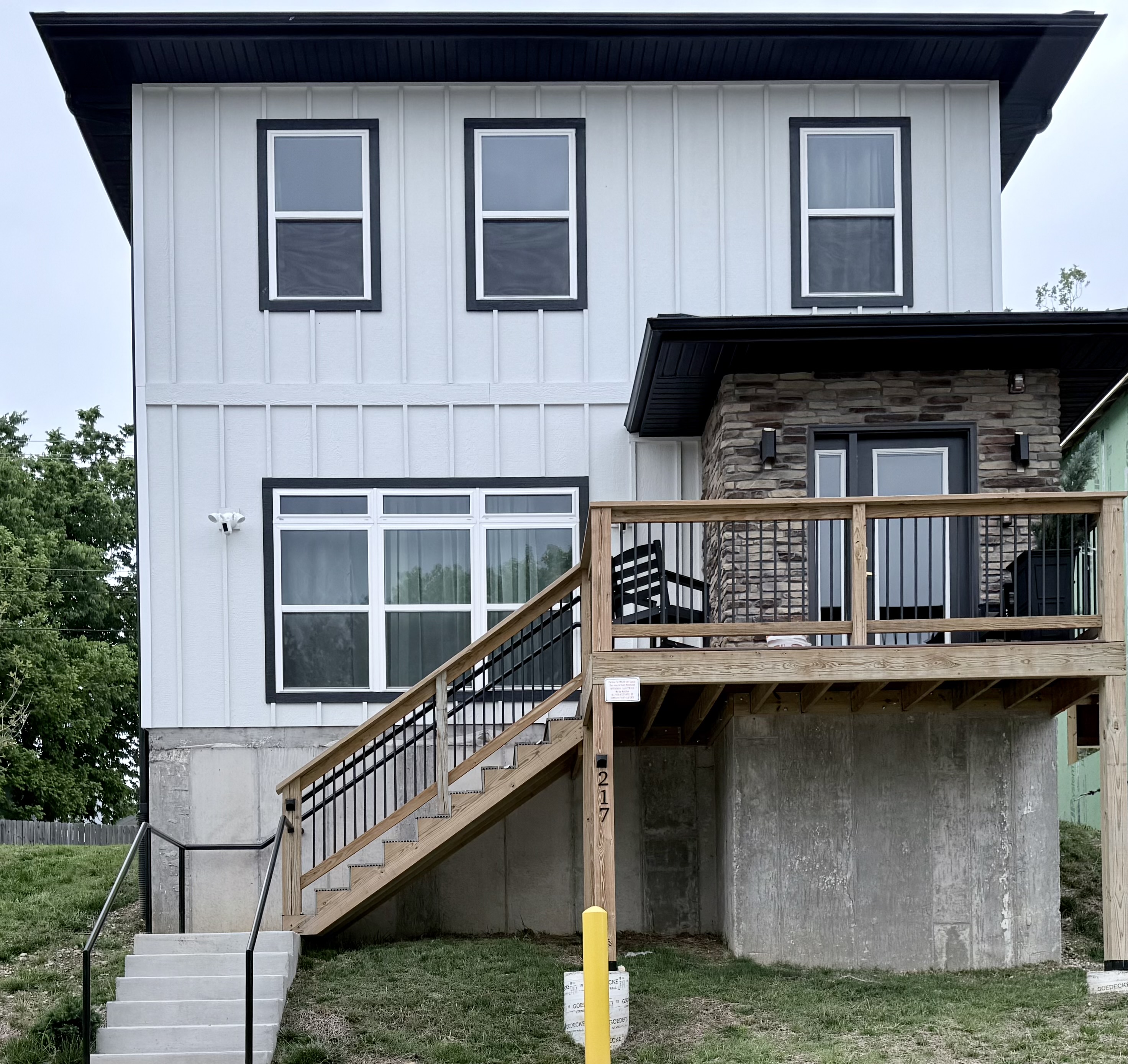 Front elevation of new vacation home with stone exterior at front door. Steps can be avoided by parking in rear parking space. Spacious with nine foot ceilings.