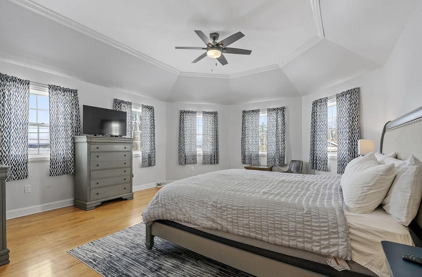 This serene primary bedroom offers panoramic lake views, along with a king bed, TV, desk+chair,  and generous closet space for a comfortable extended stay.