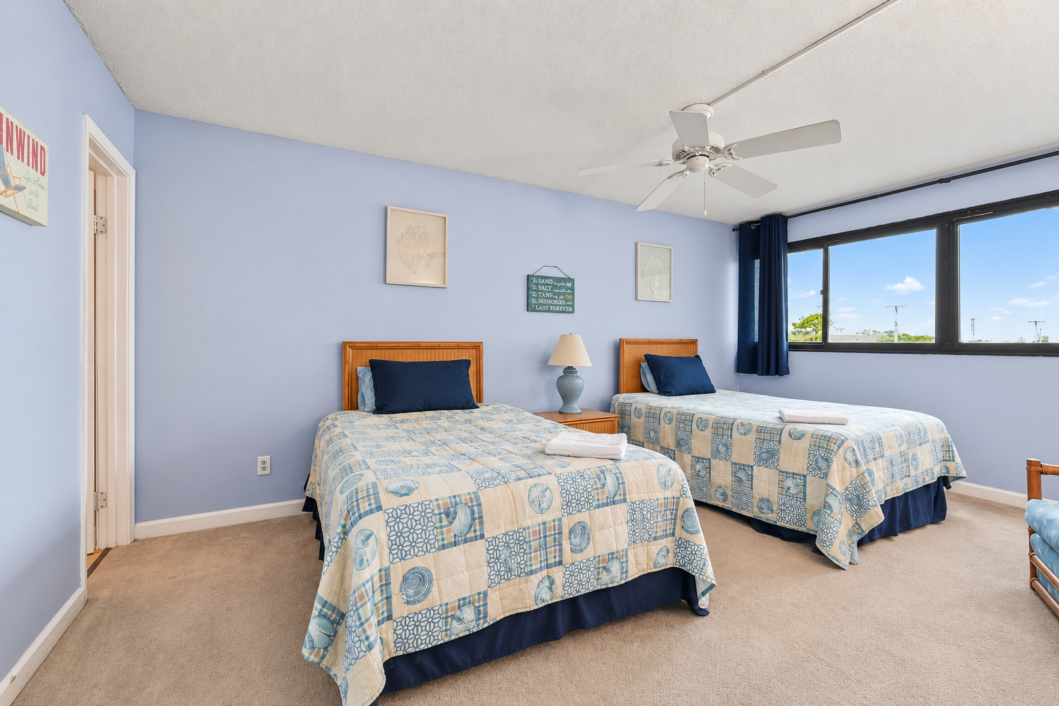 Second Bedroom with two full beds, ceiling fan, wide window view, and ensuite bathroom access.
