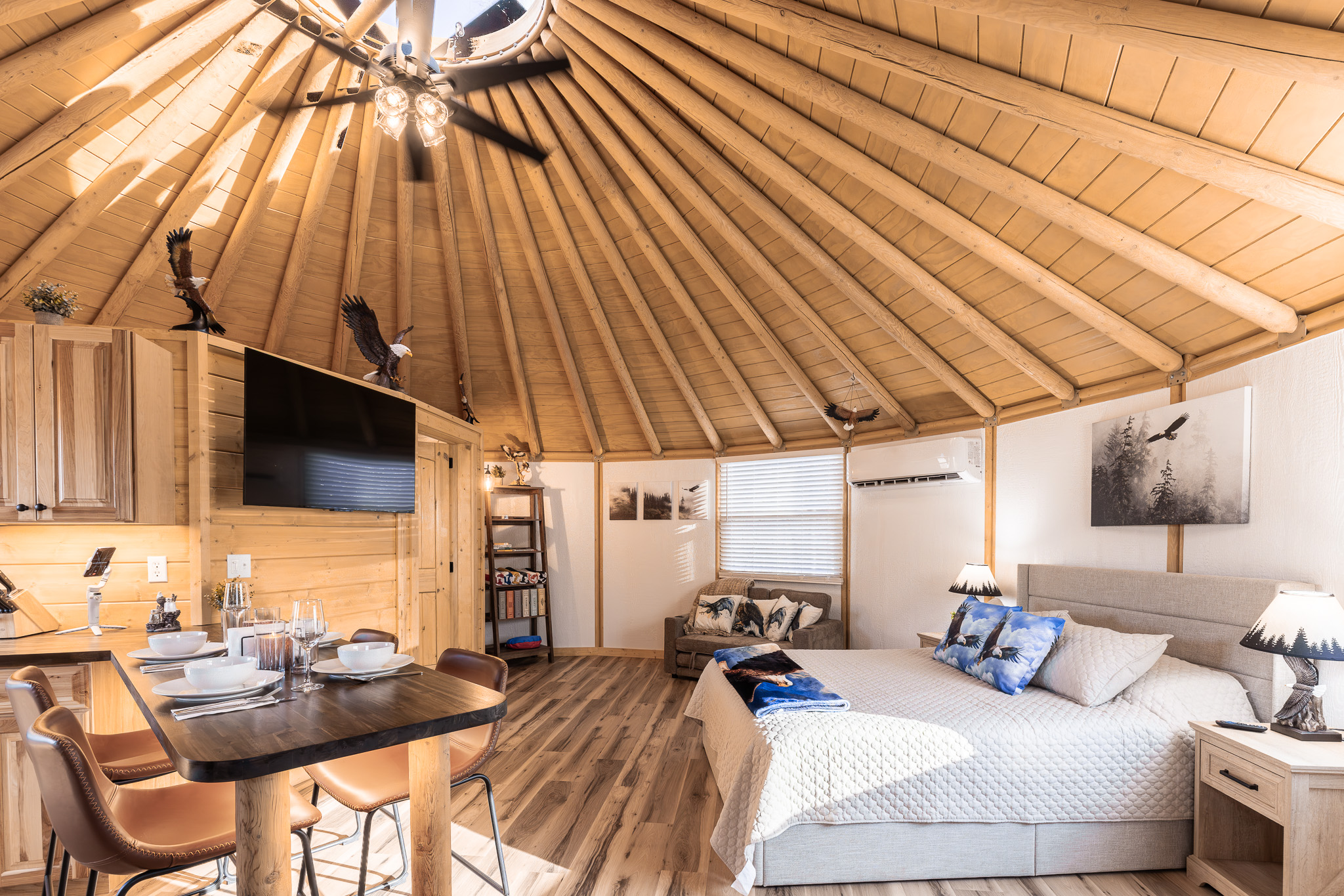 Open-concept dome living with king bed, dining area, and soaring wood ceiling