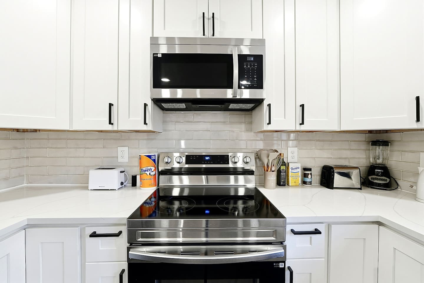 Bright white kitchen with a sleek, extended layout and ample counter space. The long layout offers plenty of countertop space, perfect for cooking, prepping, and everyday meals. Fully stocked with everything you need for a comfortable stay!
