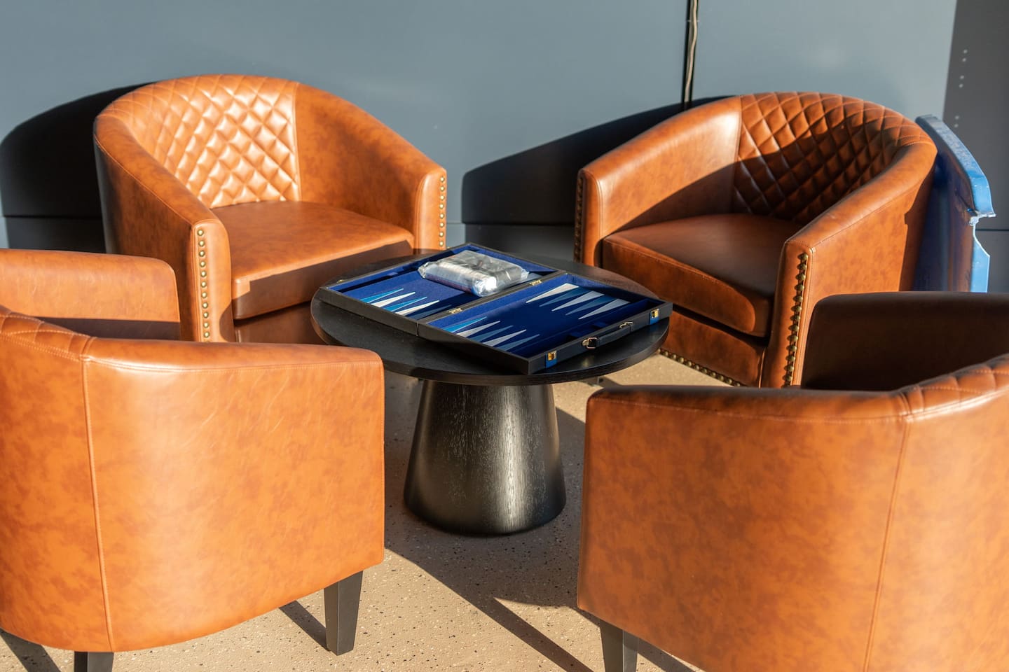 Cozy lounge corner with leather chairs and a backgammon set for relaxed game nights.