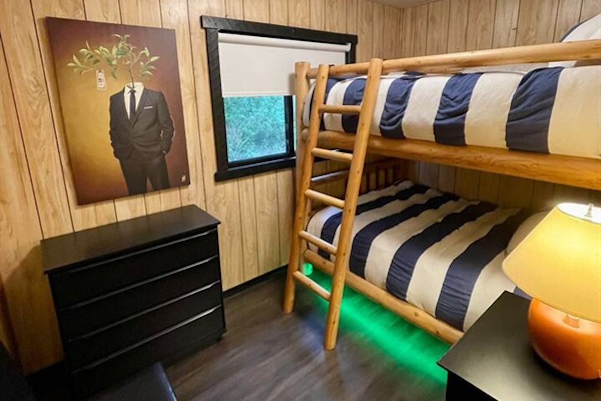Bunk bedroom with dresser and colorful accent lighting