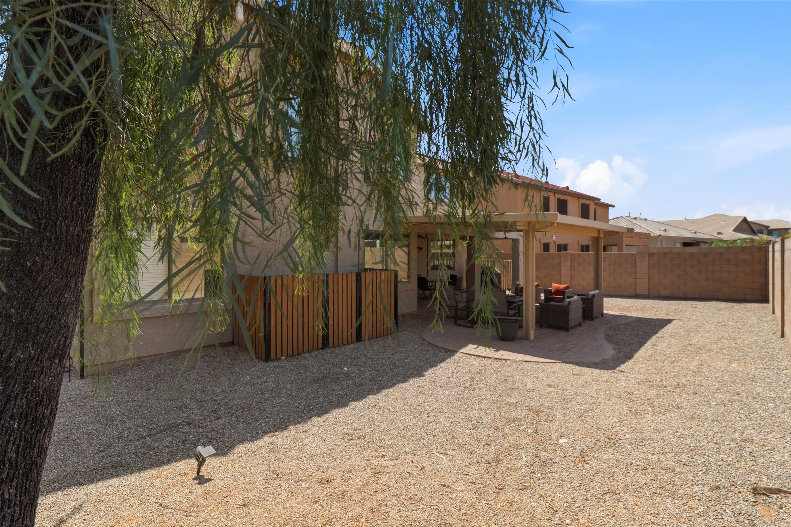 Backyard with a shaded patio, outdoor seating, and a wide gravel yard with room to spread out.
