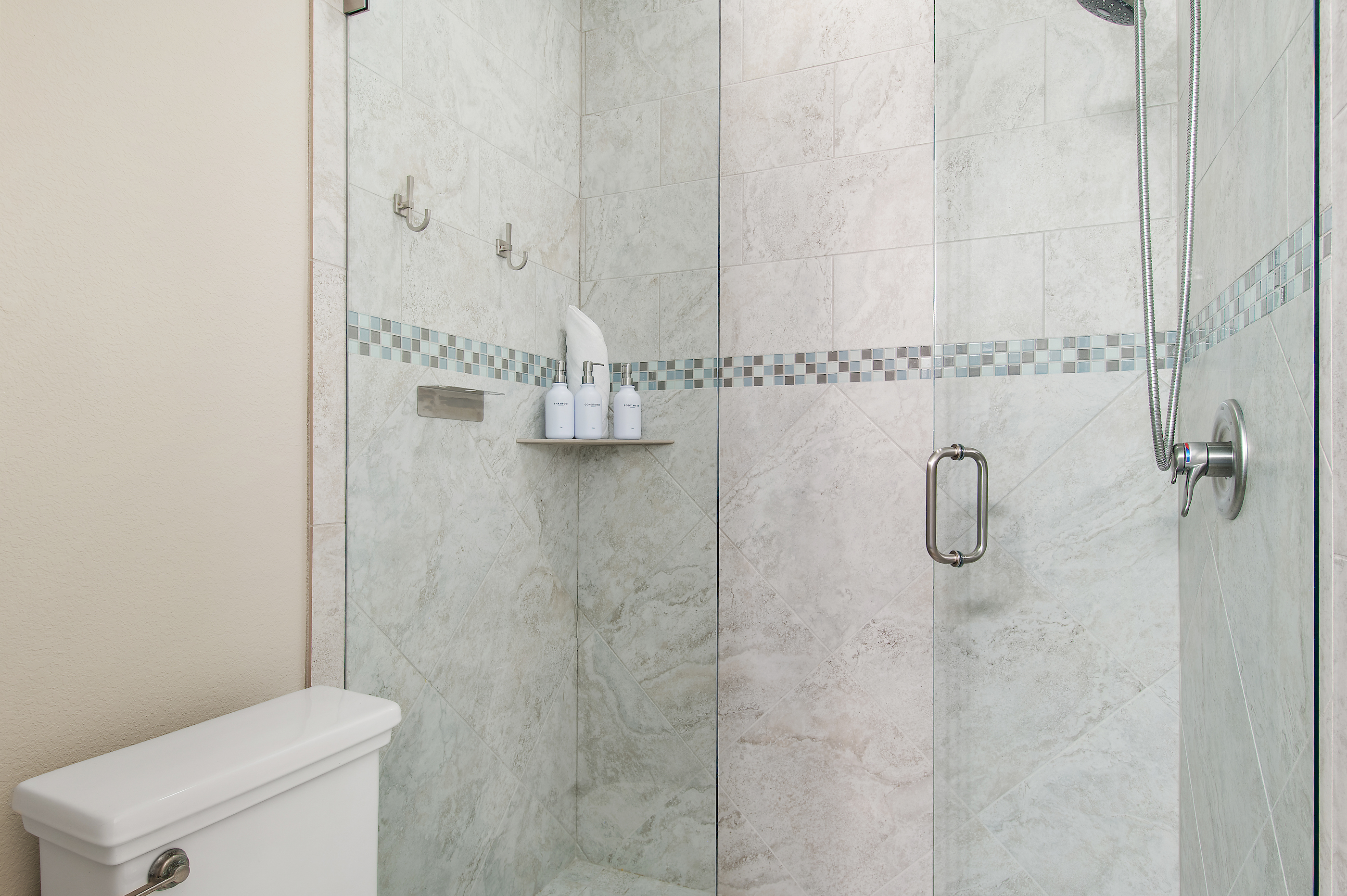 Bright, spacious bathroom with a walk in shower, generous vanity, and elegant coastal details.
