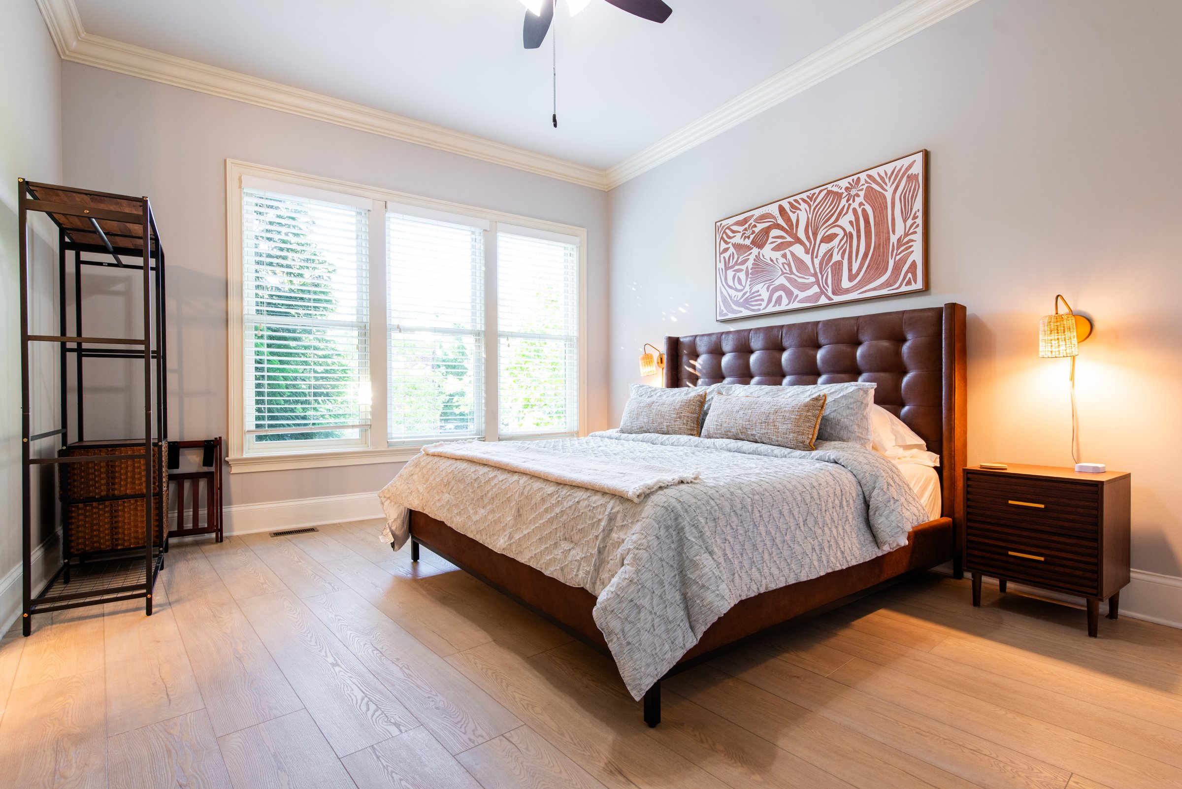 A second bedroom with a tufted leather headboard and private ensuite bath.