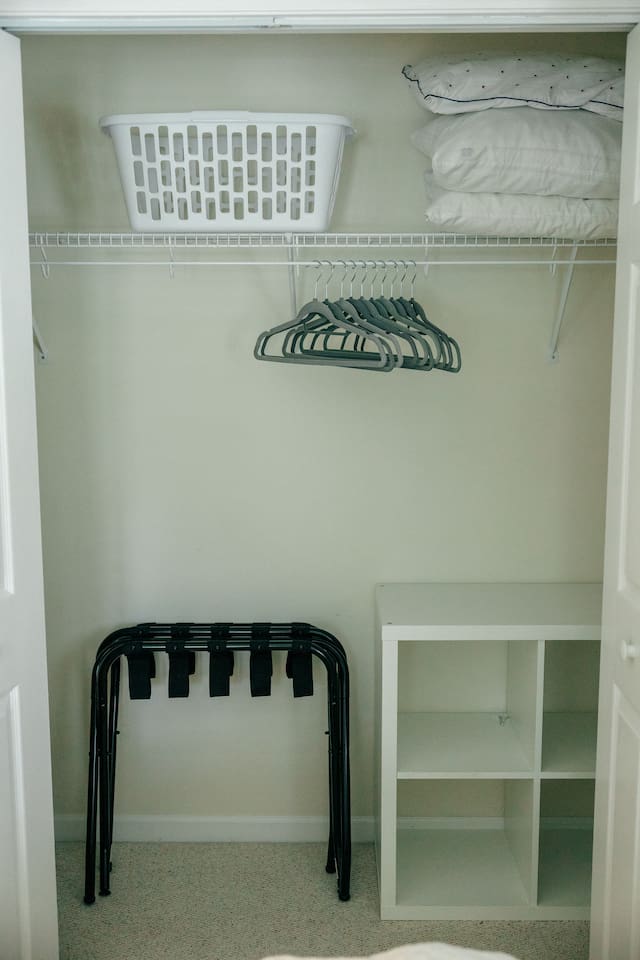 Ample closet space with 2 luggage racks, hangers, laundry basket, and extra pillows. 