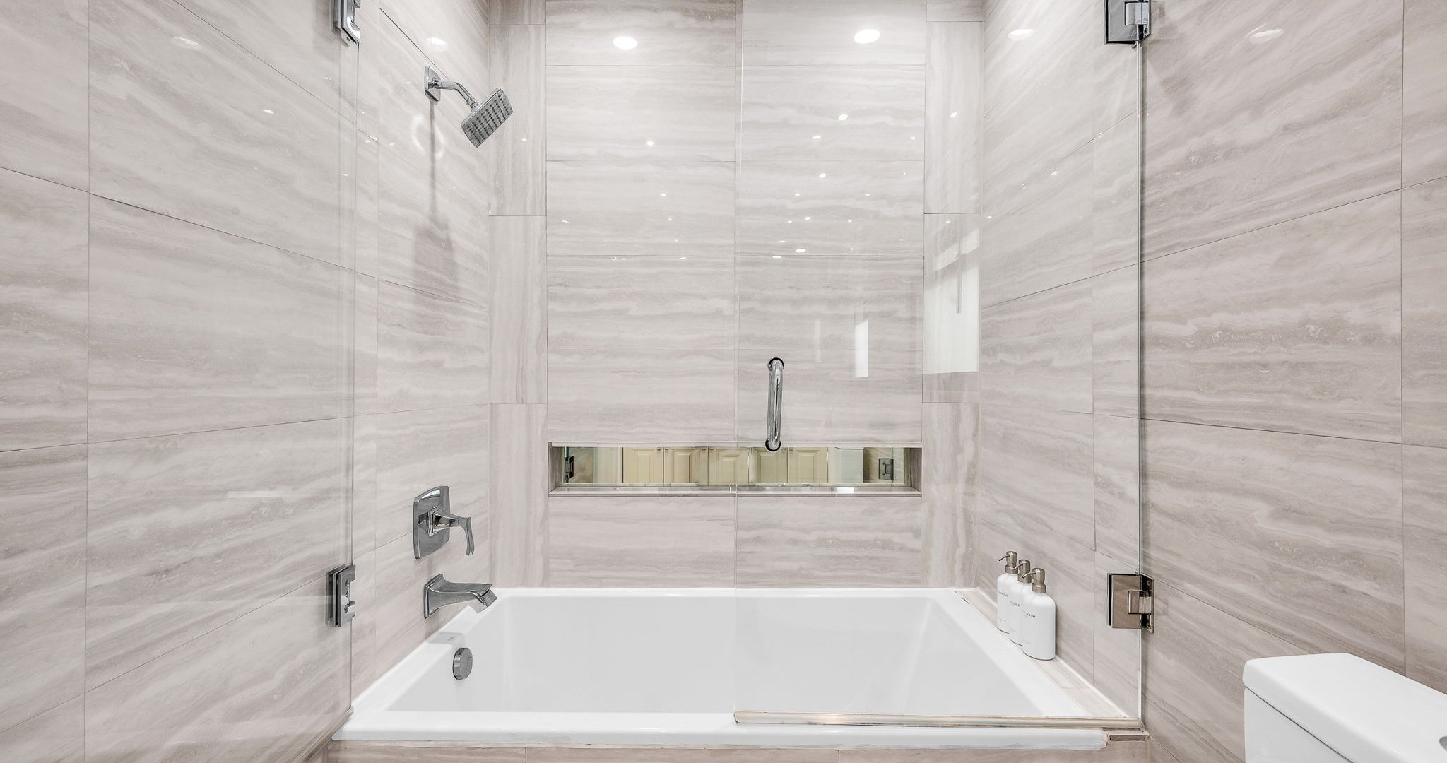The ensuite bathroom features a sleek double vanity, elegant stone finishes, and a spa-like shower/tub combo with glass enclosure. Designed for both style and comfort, it’s the perfect space to refresh and unwind