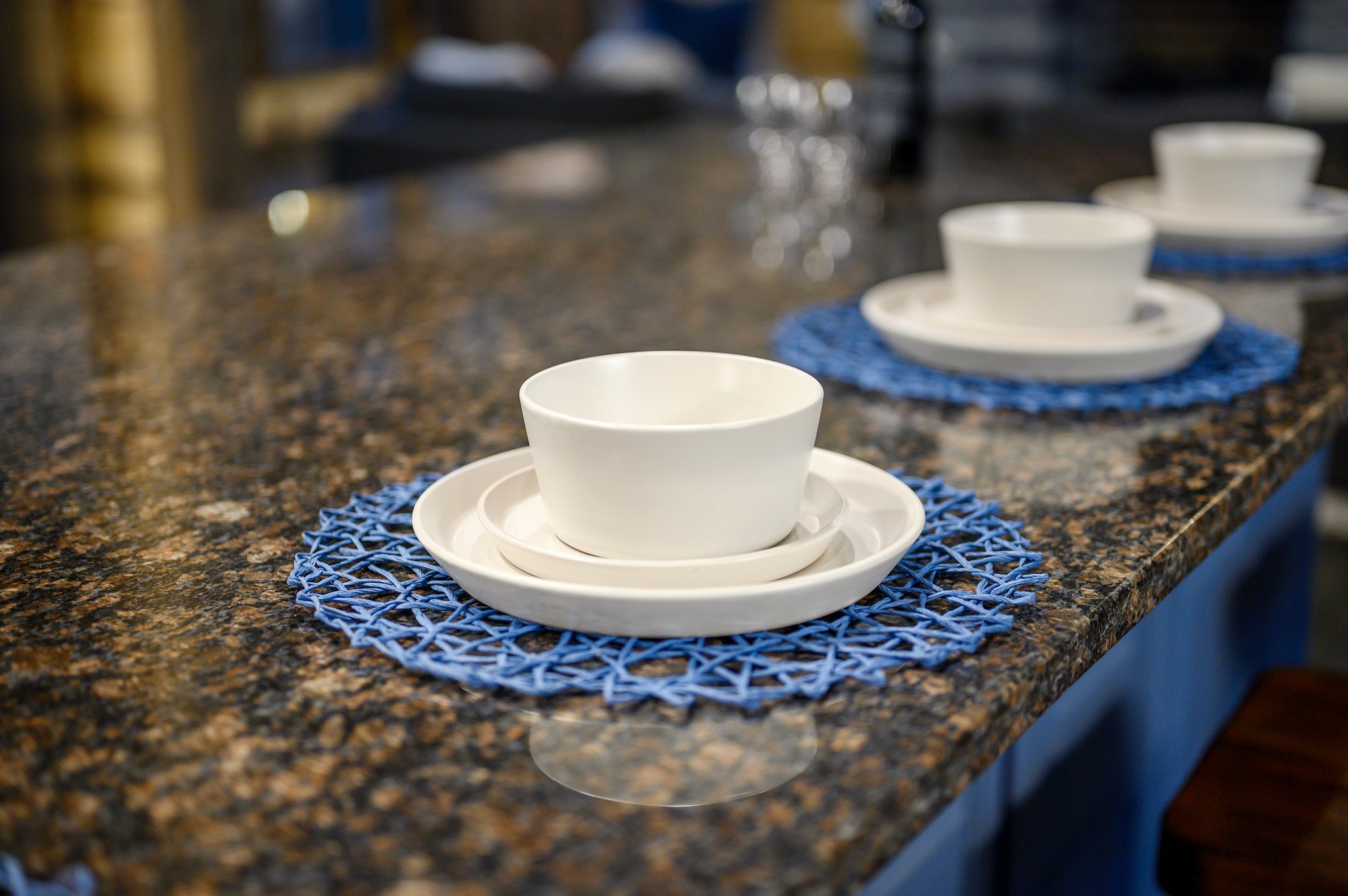Elegant granite breakfast bar with designer seating and forest views.