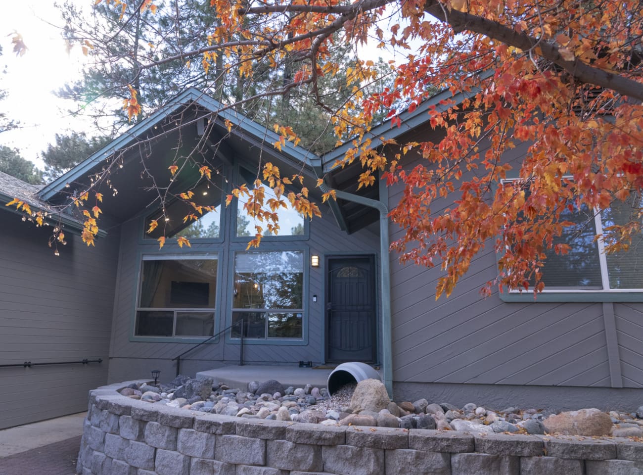 Home entrance with stone details, tree cover, and a cozy seasonal feel