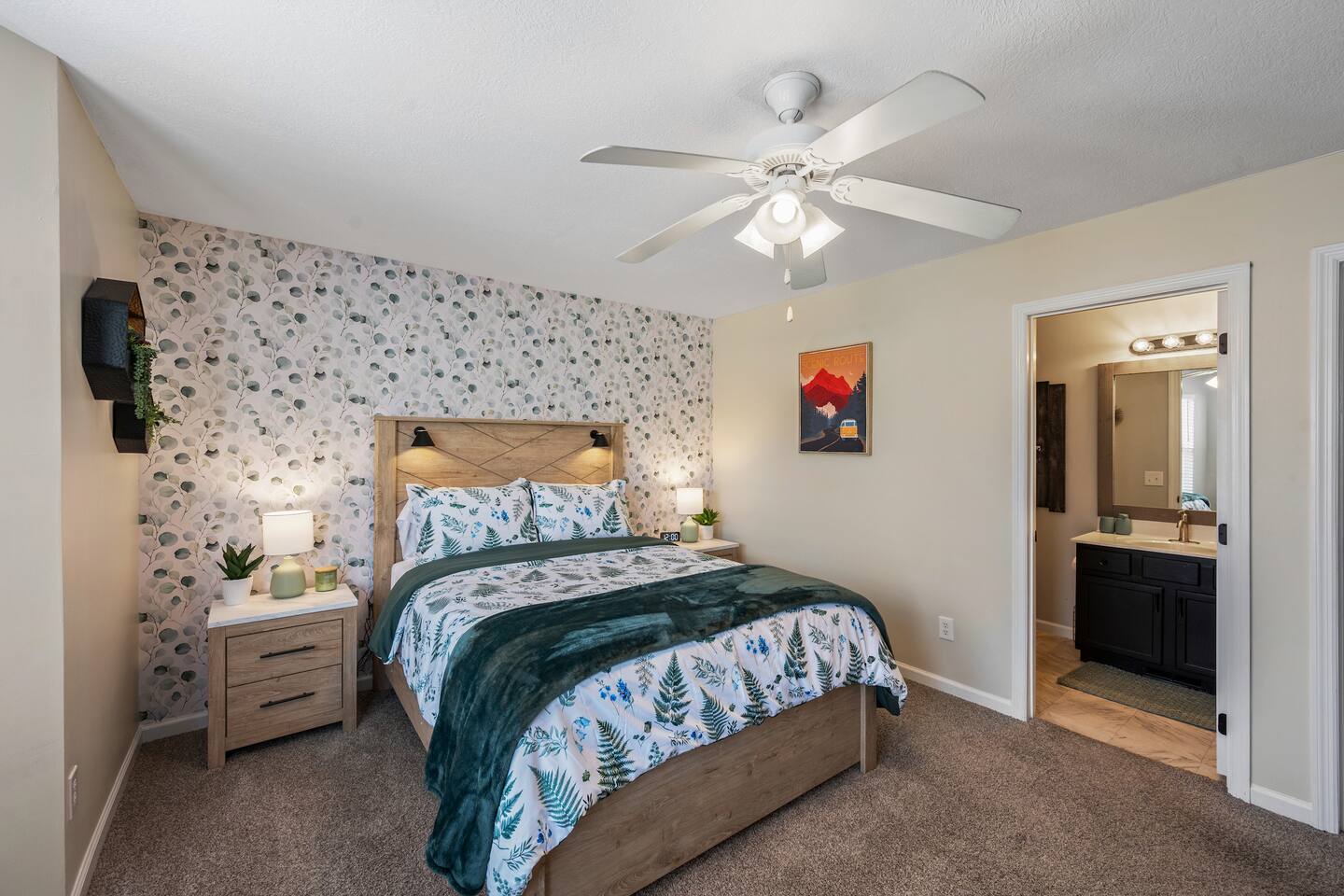 Inviting bedroom with a queen bed, accent wallpaper, cozy lighting, ceiling fan, and private en-suite bathroom—perfect for a comfortable stay.