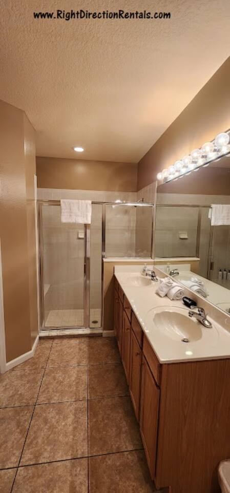 Spacious bathroom featuring a large vanity, tile shower, and clean neutral finishes.