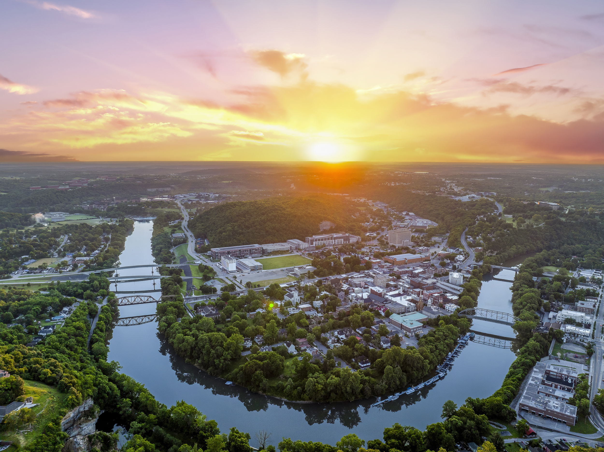 The Kentucky River curves through Frankfort at golden hour, framed by limestone cliffs and rolling green hills.