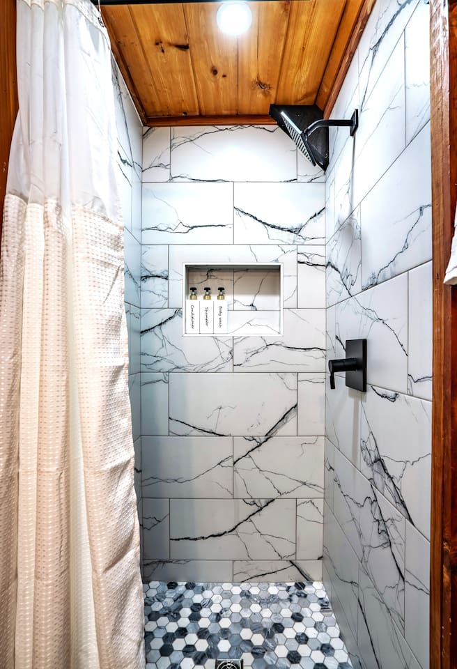 This is the second bathroom located in the loft area featuring a luxurious white-tiled standing shower, perfect for a spa-inspired cabin bathroom retreat and unwinding in style.